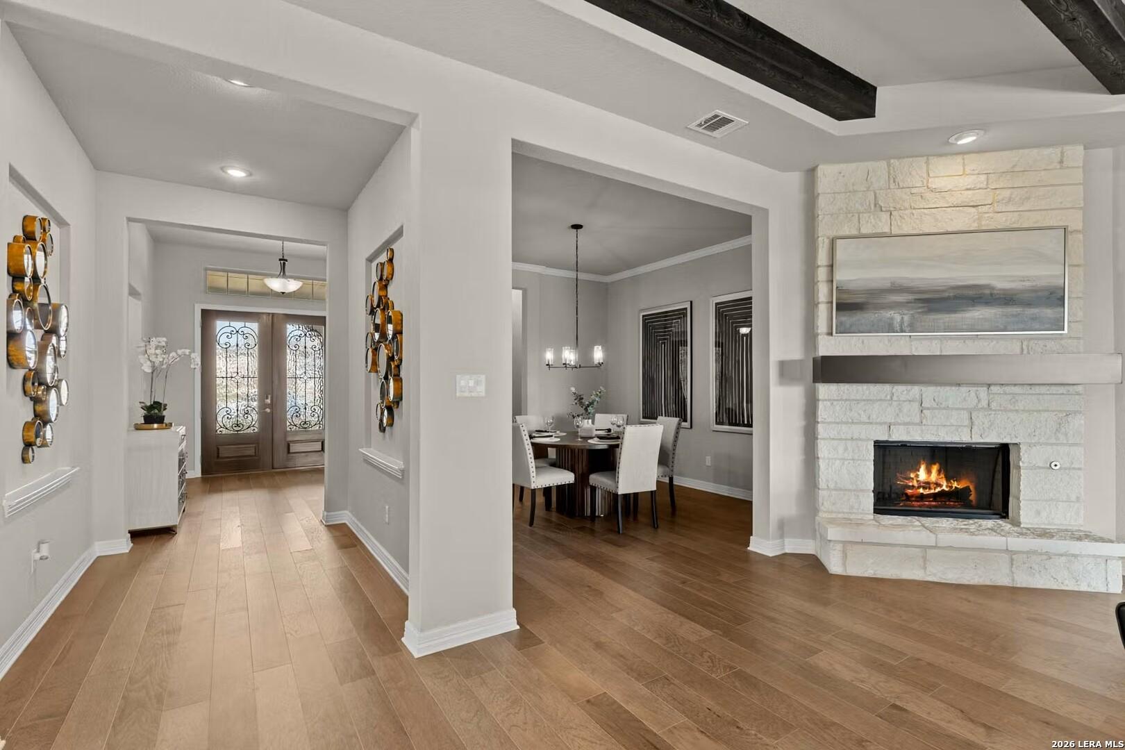 Open-concept living room with stone fireplace and dining area in The Summerlin C home by Davidson Homes, Castroville, TX.
