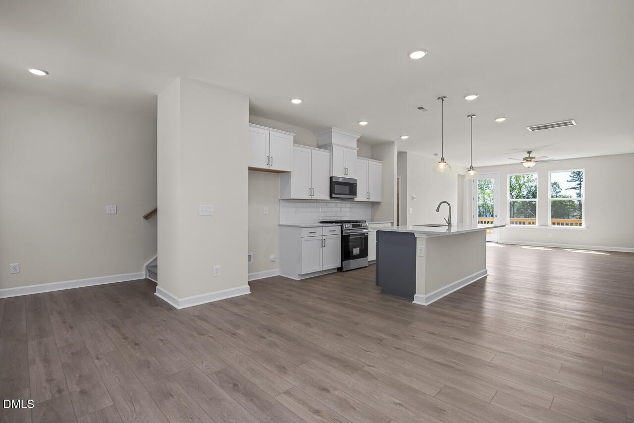 Open-concept kitchen with white cabinets and island in The Mitchell floor plan at Camden Park, Knightdale, NC.