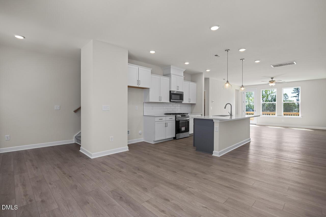 Open-concept kitchen with white cabinets and island in The Mitchell floor plan at Camden Park, Knightdale, NC.