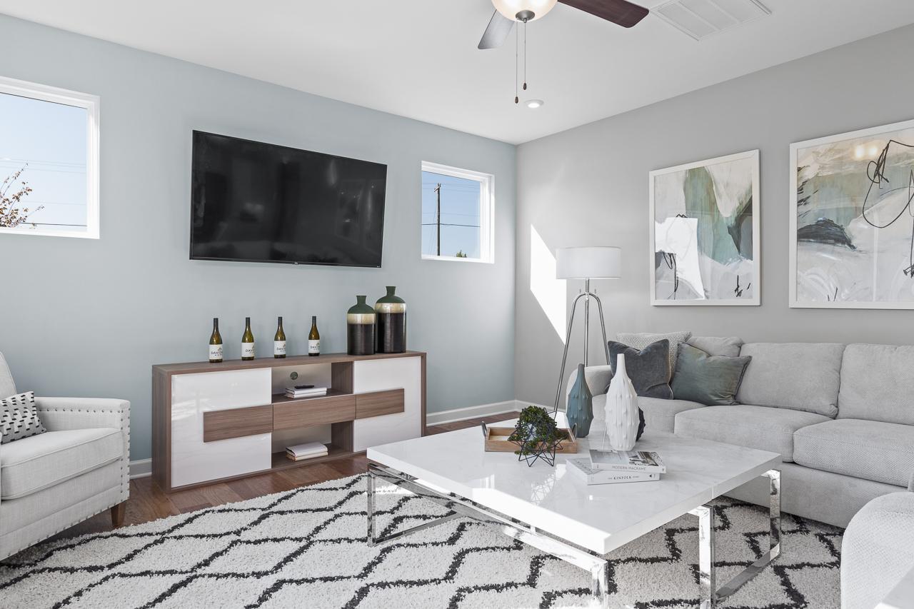 Bright, modern living room in The Hemlock A featuring a white marble coffee table, plush sofa, and wall-mounted TV.