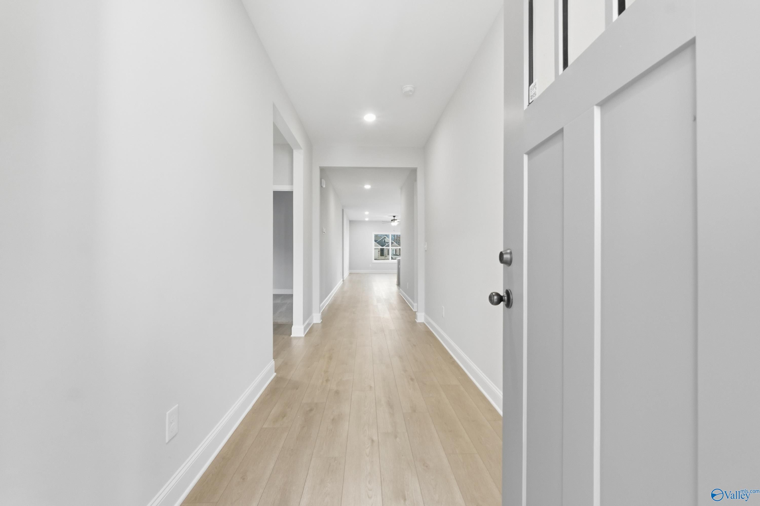 Bright hallway with light oak floors, white walls, and recessed lighting in The Daphne C 4-bedroom home, Athens, Alabama