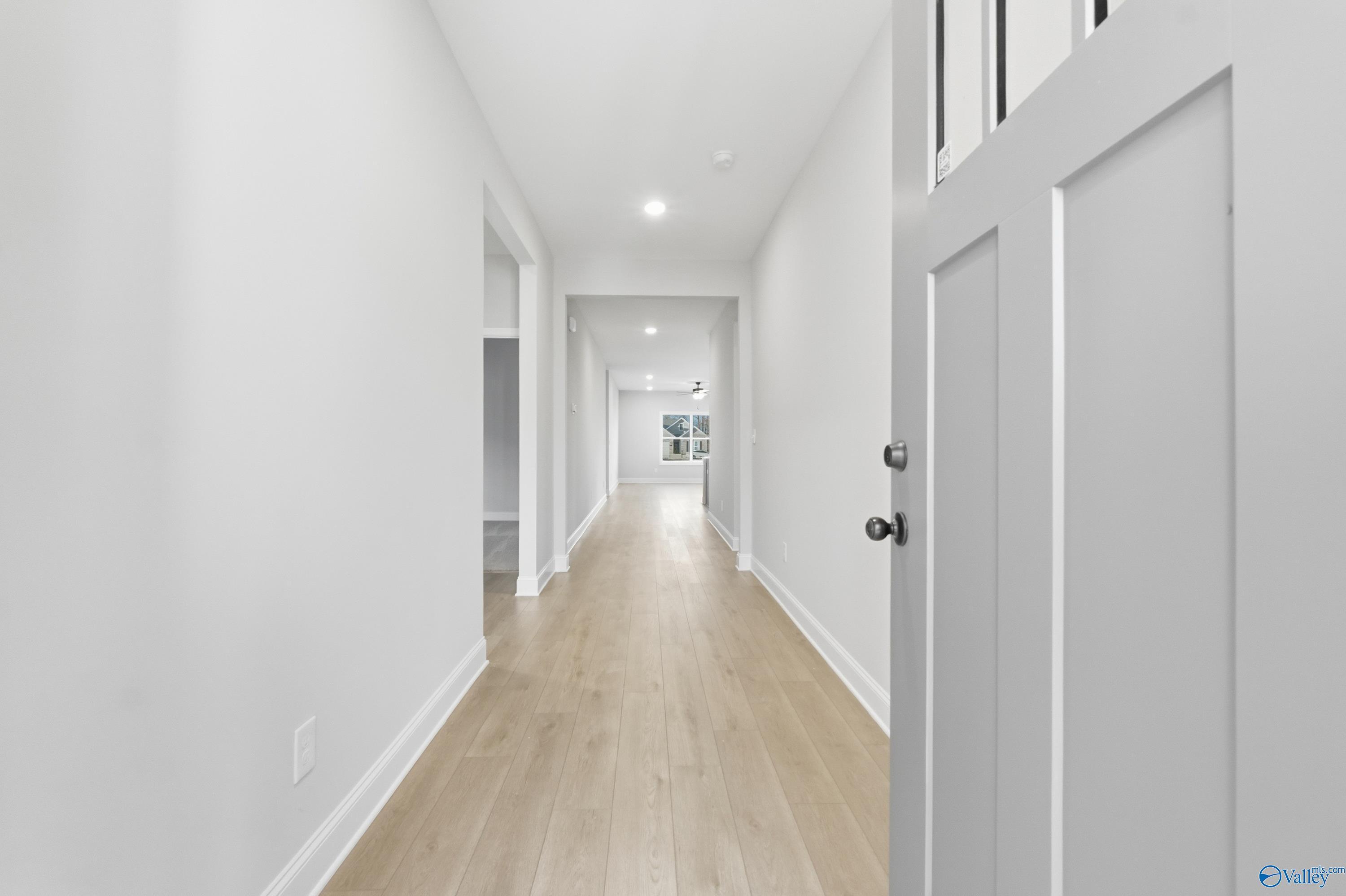 Bright hallway with light oak floors, white walls, and recessed lighting in The Daphne C 4-bedroom home, Athens, Alabama