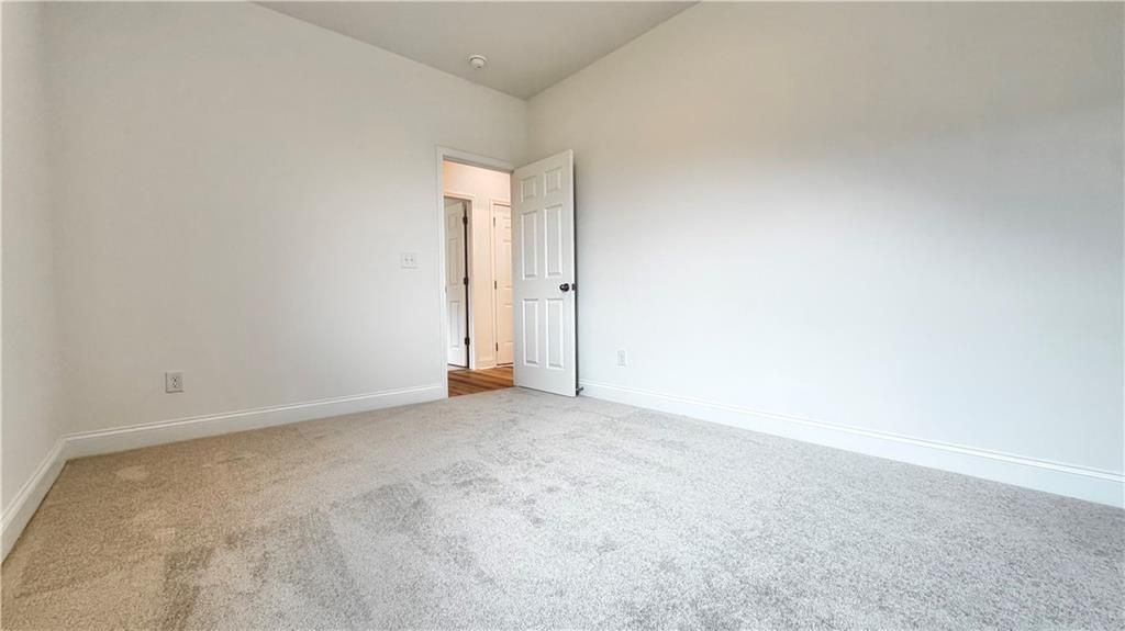 Bright spare bedroom with neutral carpet in The Glenwood A floor plan at Wehunt Meadows, Hoschton, Georgia.