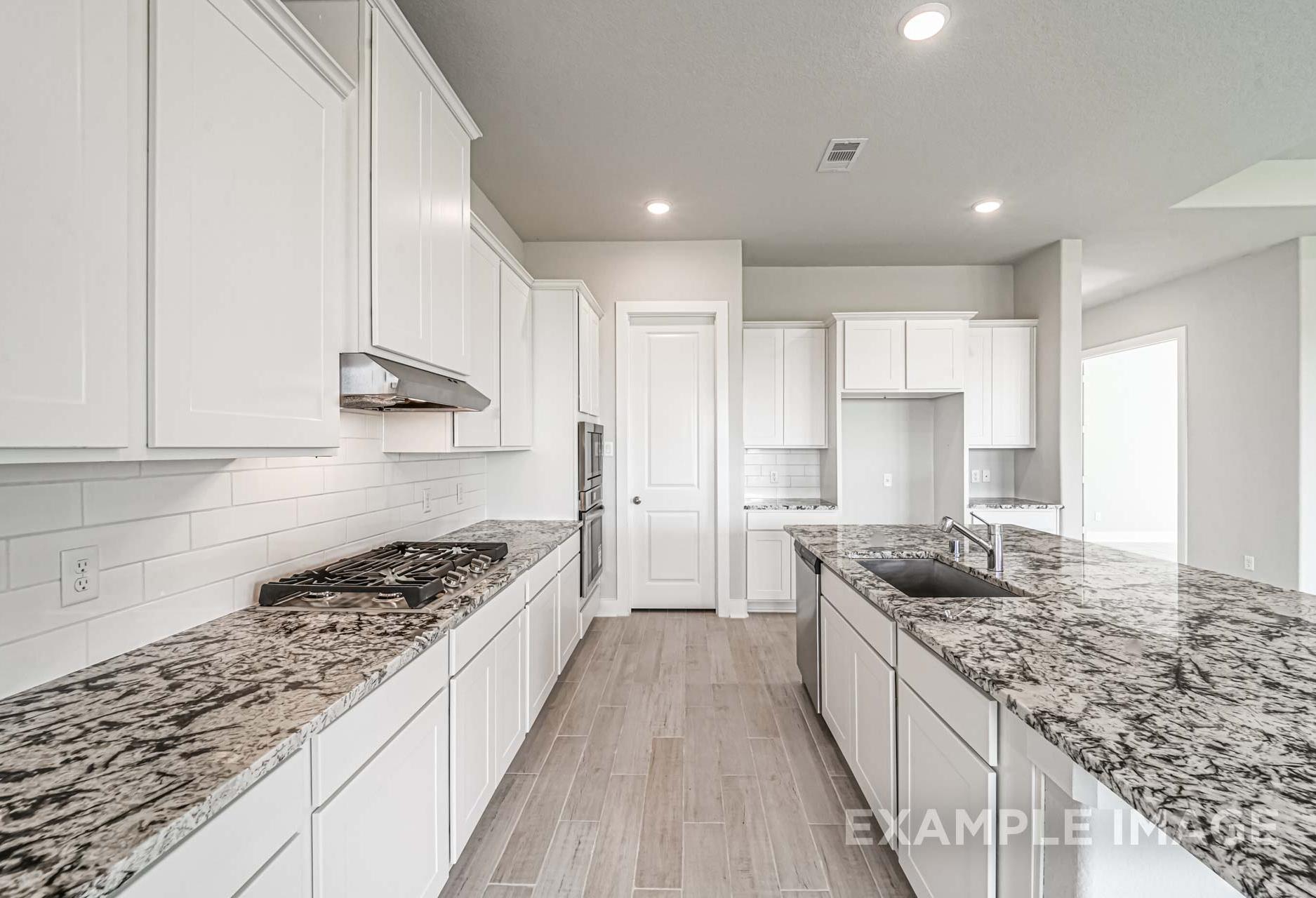 Spacious kitchen in The George A by Davidson Homes featuring white cabinets, granite countertops, subway tile backsplash, and hardwood floors