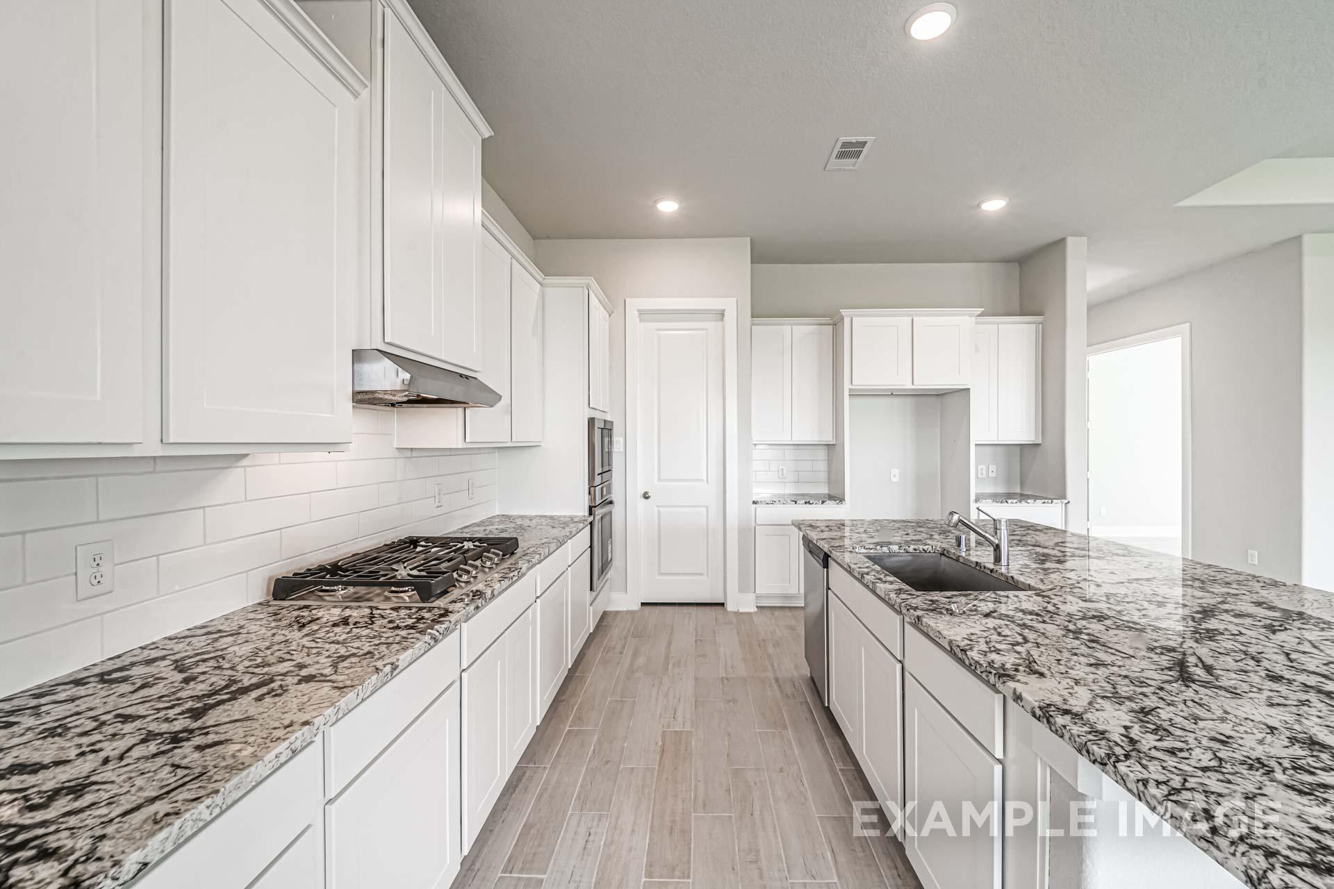 Spacious kitchen in The George A by Davidson Homes featuring white cabinets, granite countertops, subway tile backsplash, and hardwood floors
