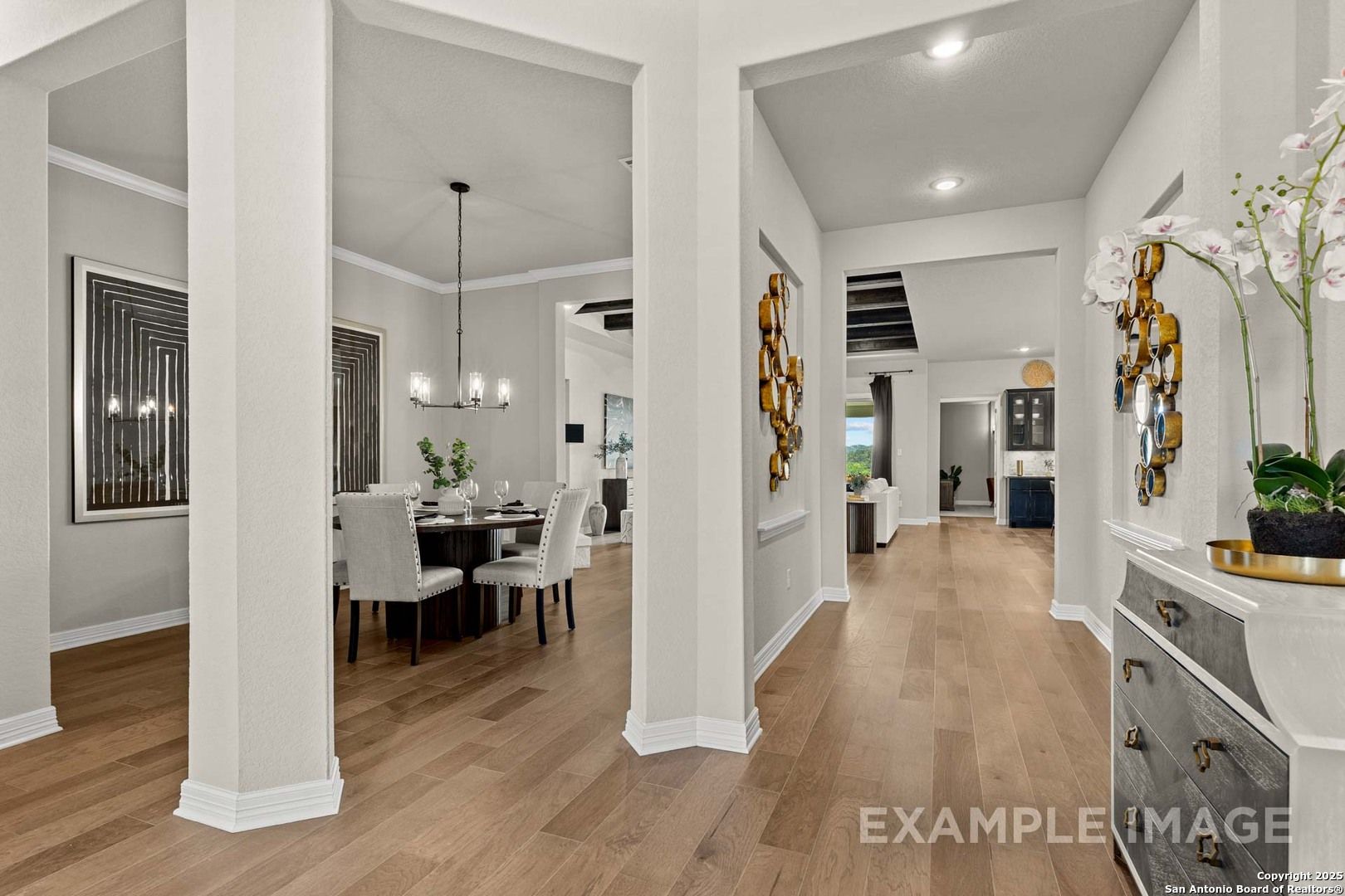 Elegant formal dining room with wooden table, white chairs, and chandelier open to hallway in Davidson Homes The Summerlin B, Castroville, Texas