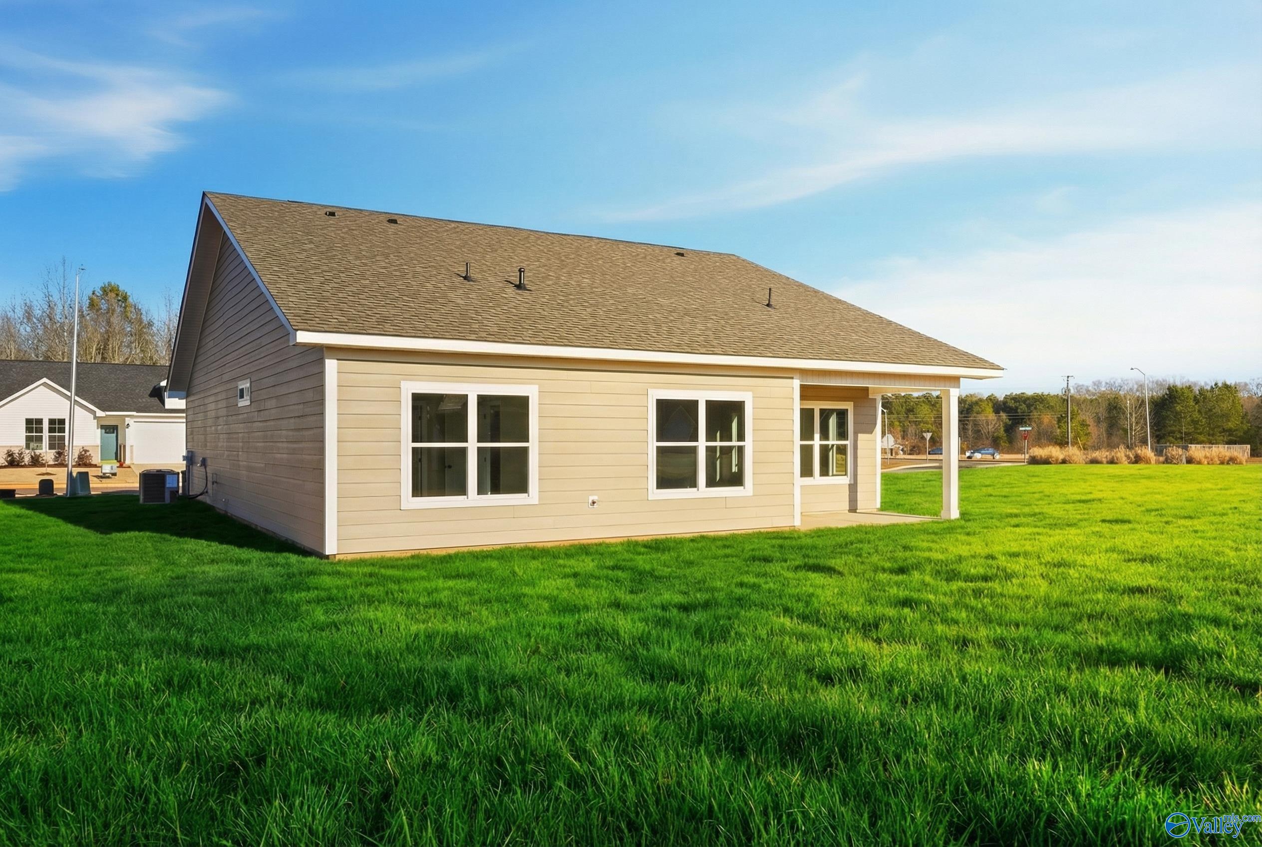 Beige single-story 3-bedroom home with gabled roof, covered porch, and lush green lawn in Forest Glen, Hazel Green, Alabama
