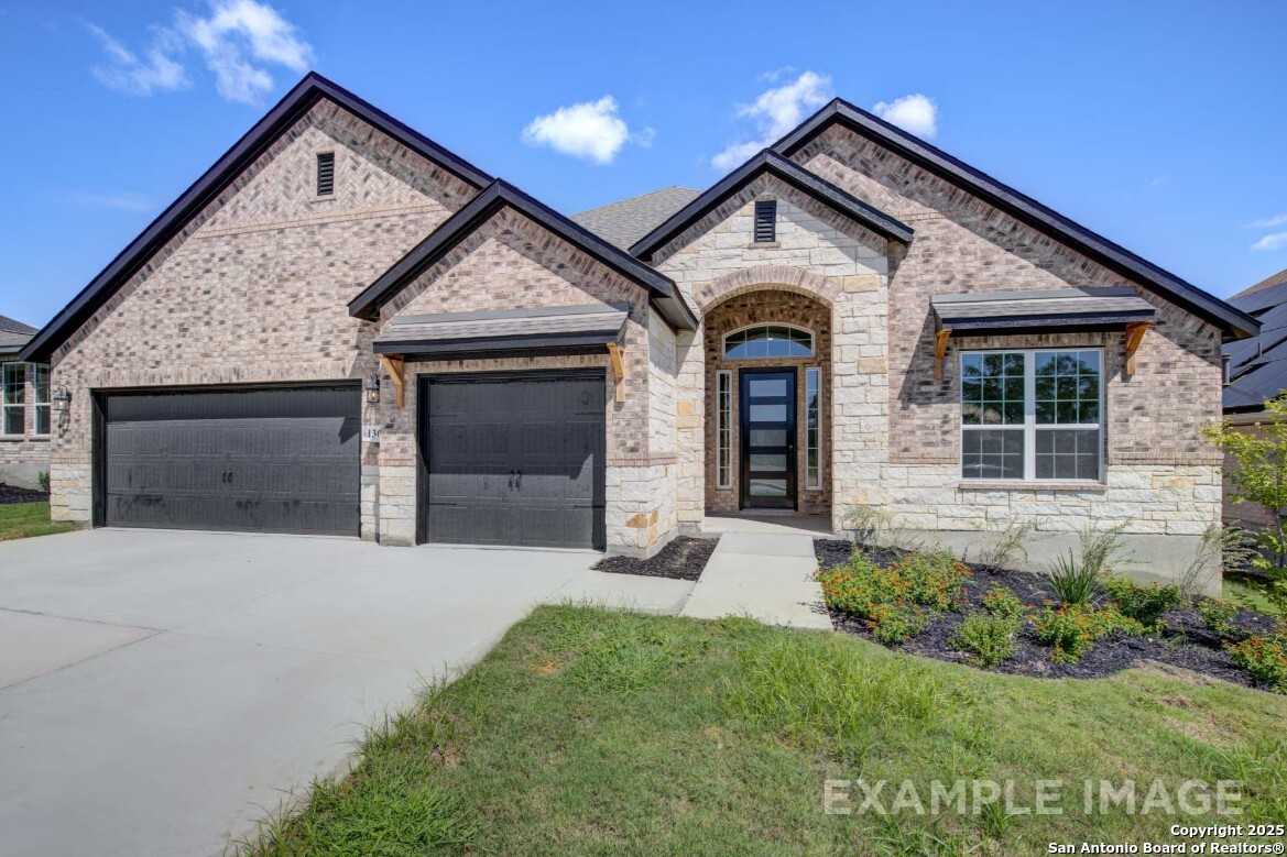 Modern brick single-story home with stone accents, arched glass entry, 2-car garage, and landscaped yard in Ladera, San Antonio