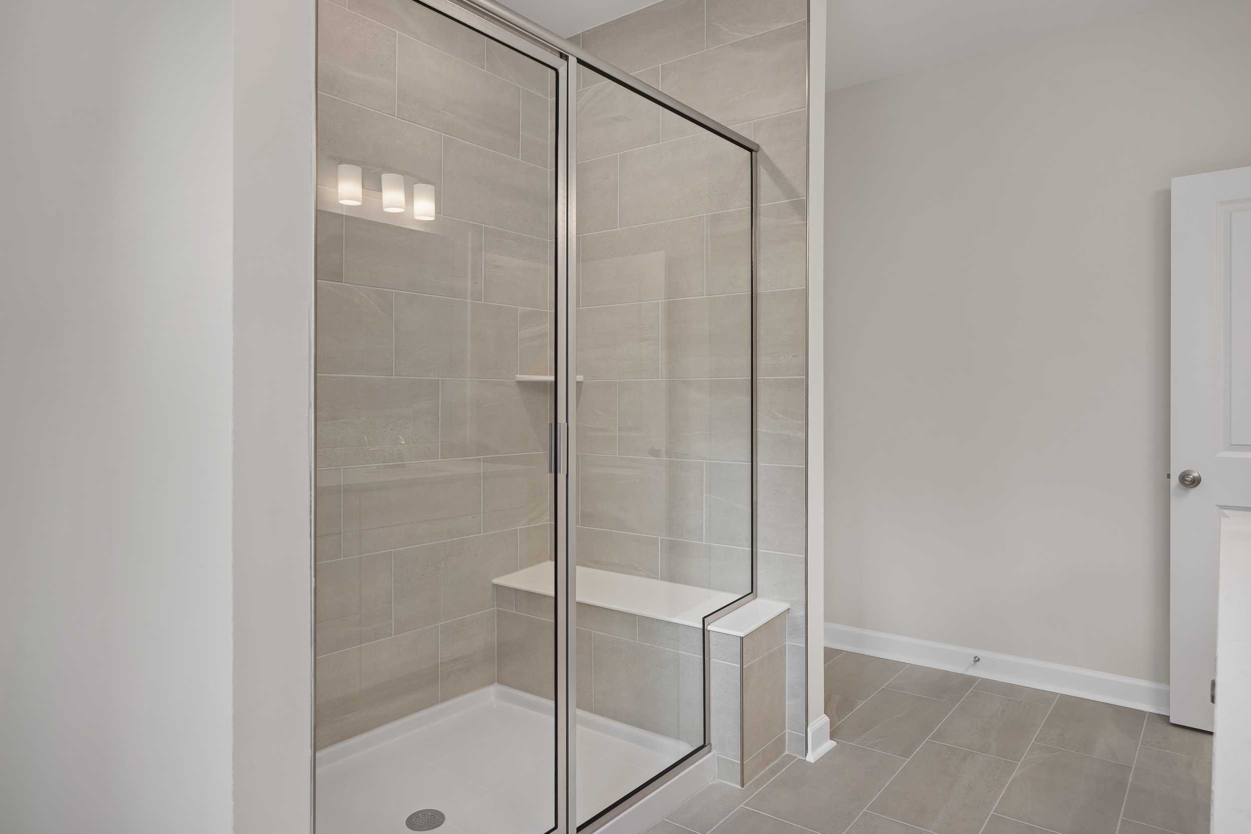Modern walk-in shower in The Beech C master bath with frameless glass enclosure, subway tile walls, and built-in bench seat
