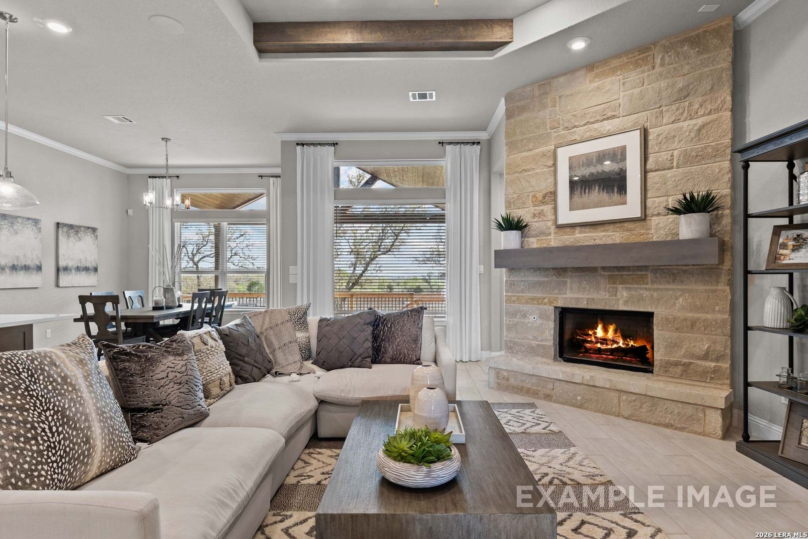 Open-concept living room with stone fireplace and wood beam ceiling in The Garner C plan at The Reserve at Potranco Oaks.