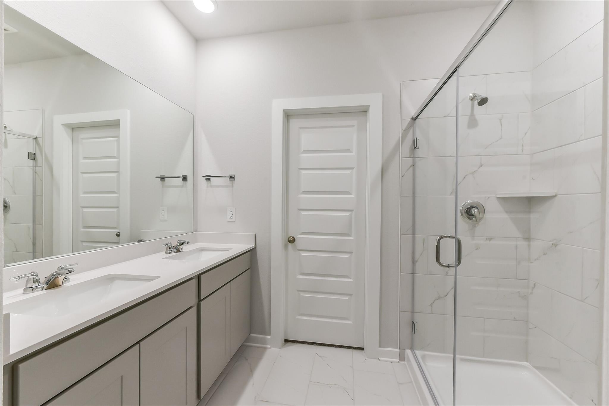 Modern master bathroom with double vanity, frameless glass shower in Davidson Homes The Brazos E, Magnolia, Texas