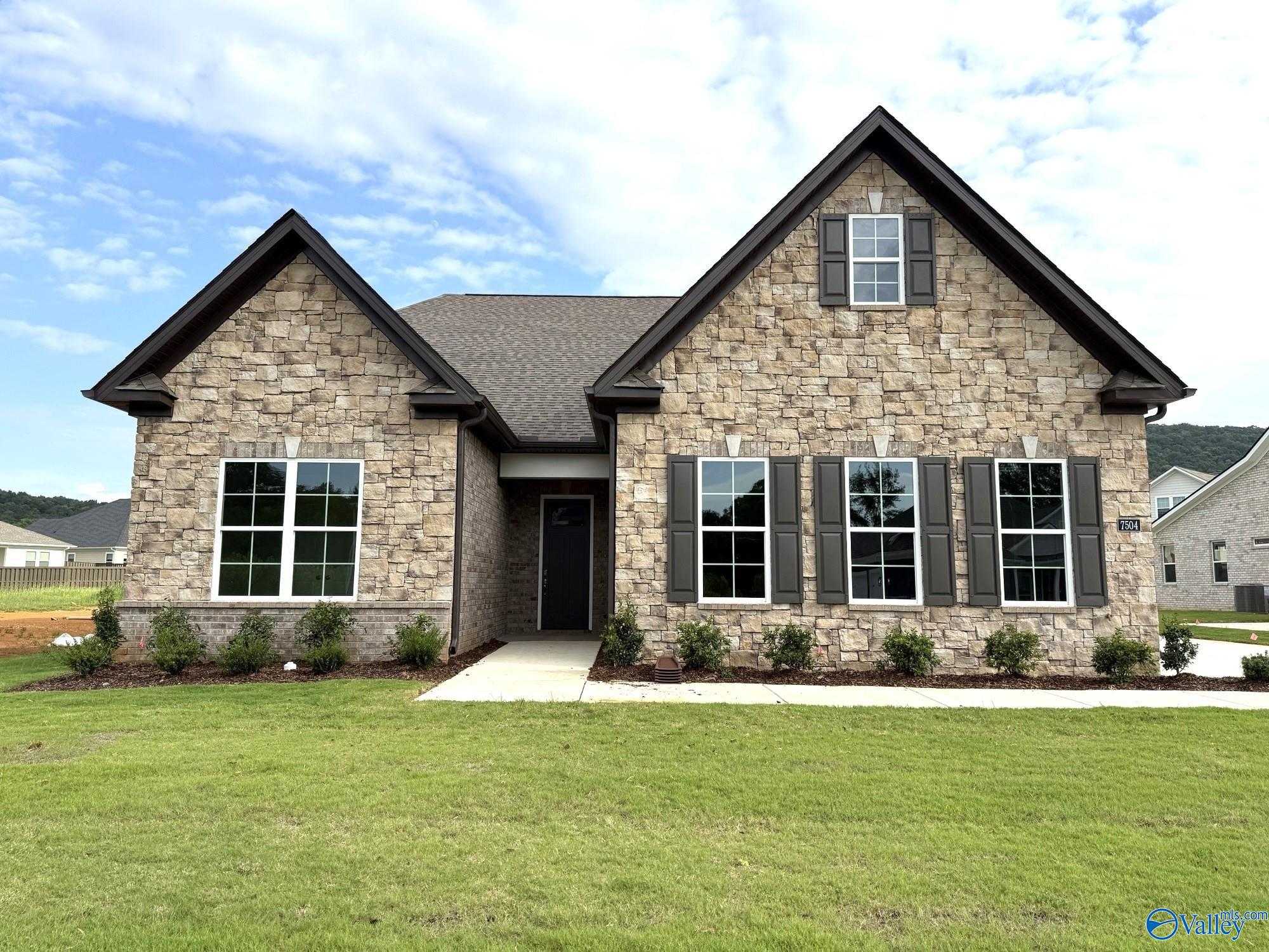 Stone facade 1.5-story The Oxford home with 2-car garage, large windows, and landscaped yard in Owens Cross Roads, Alabama