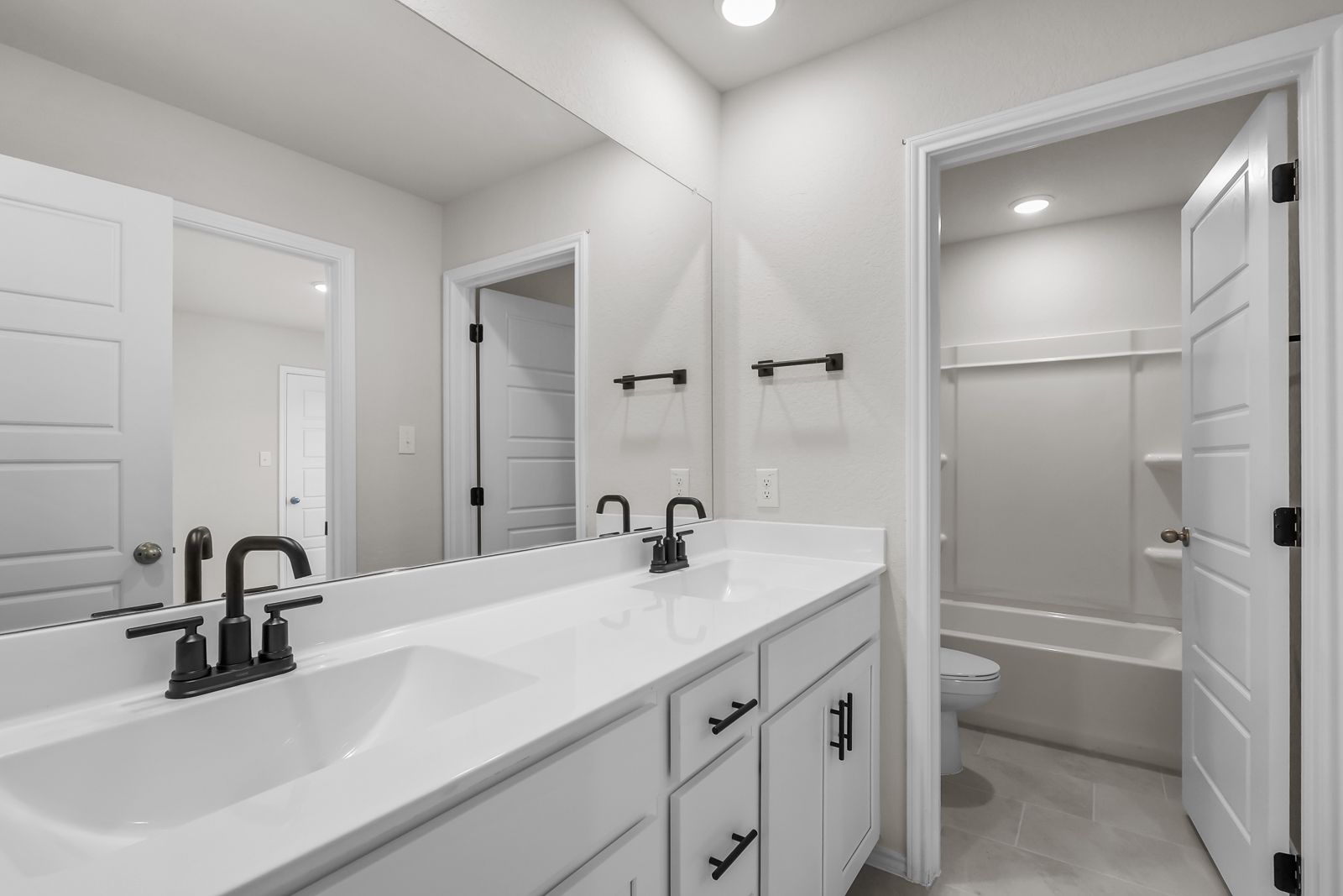 Modern bathroom in The Sequoia C featuring white vanity, dual sinks, and matte black fixtures in Converse, Texas.