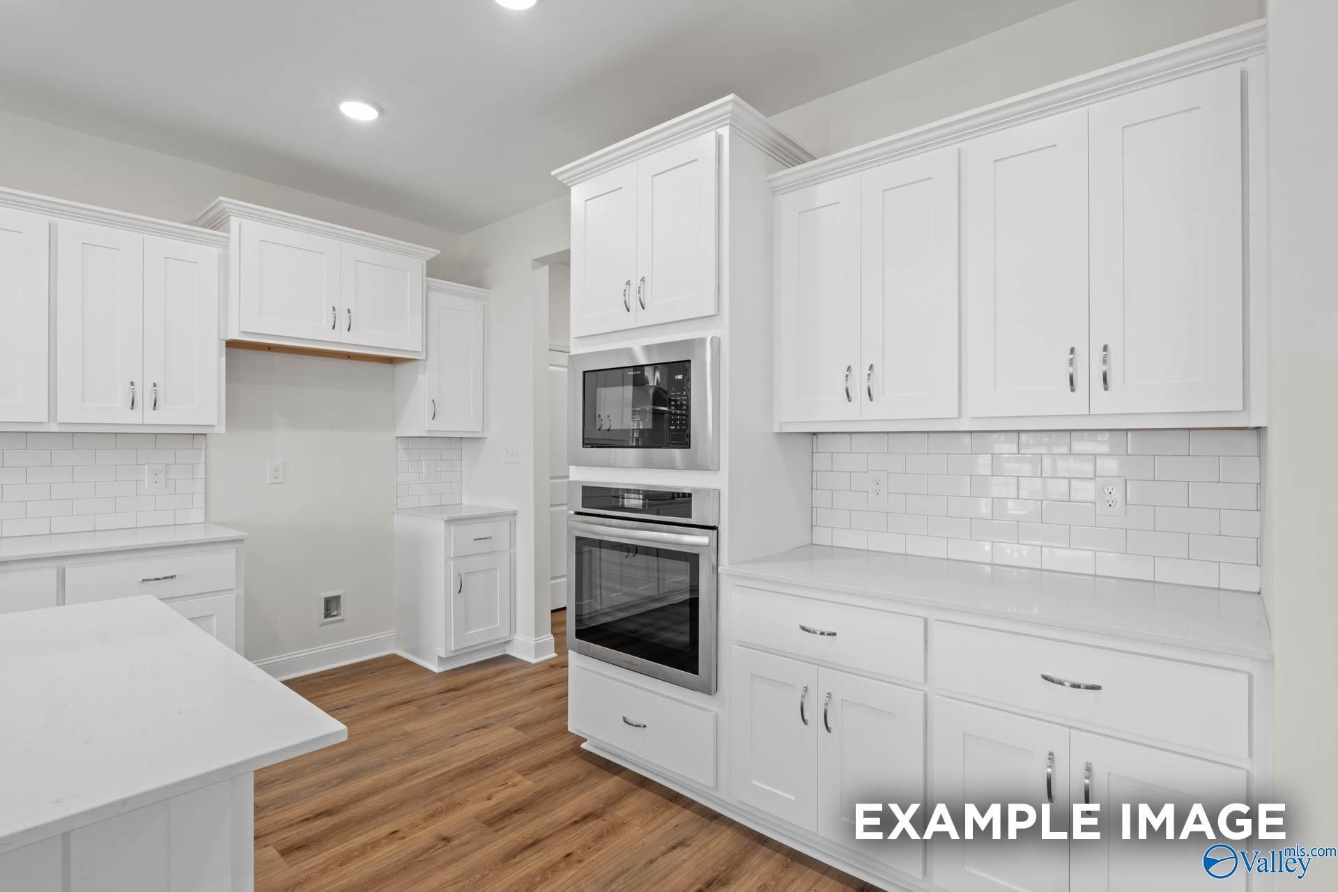 Modern white kitchen with stainless steel oven, microwave, subway tile backsplash in The Oxford floor plan, Davidson Homes Huntsville