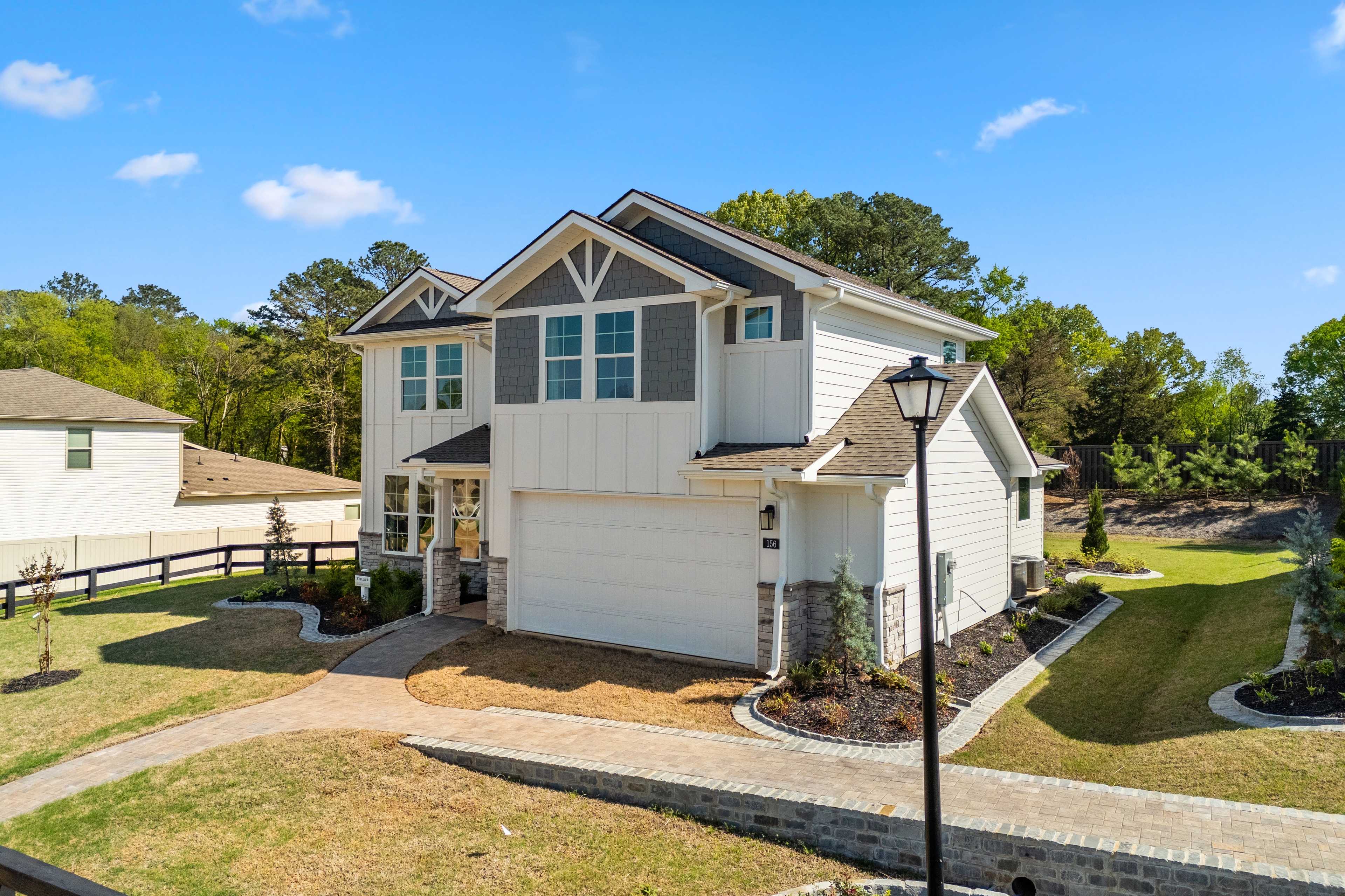 Modern two-story home exterior at Evergreen Mill in Madison, Alabama with side garage, split-rail fence, and lush landscaping