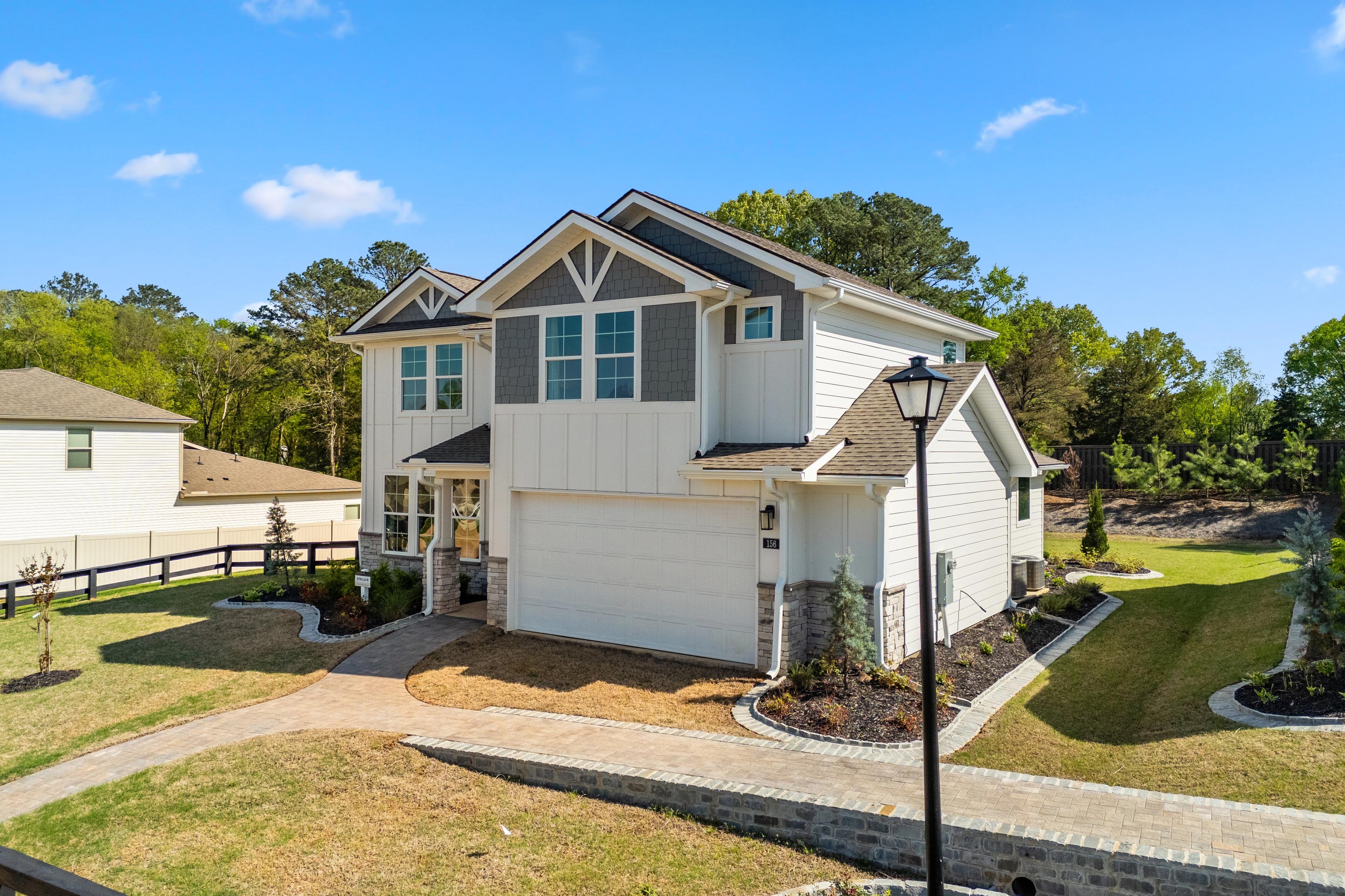 Modern two-story home exterior at Evergreen Mill in Madison, Alabama with side garage, split-rail fence, and lush landscaping