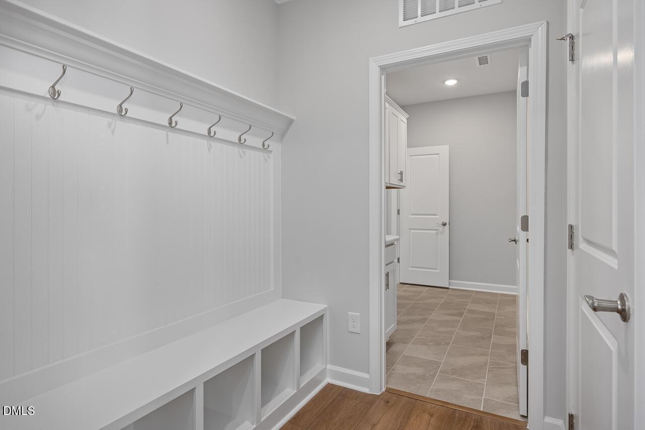 Modern mudroom with built-in bench, coat hooks, and storage in The Ashport L floor plan at Sage on North Main, Wake Forest.