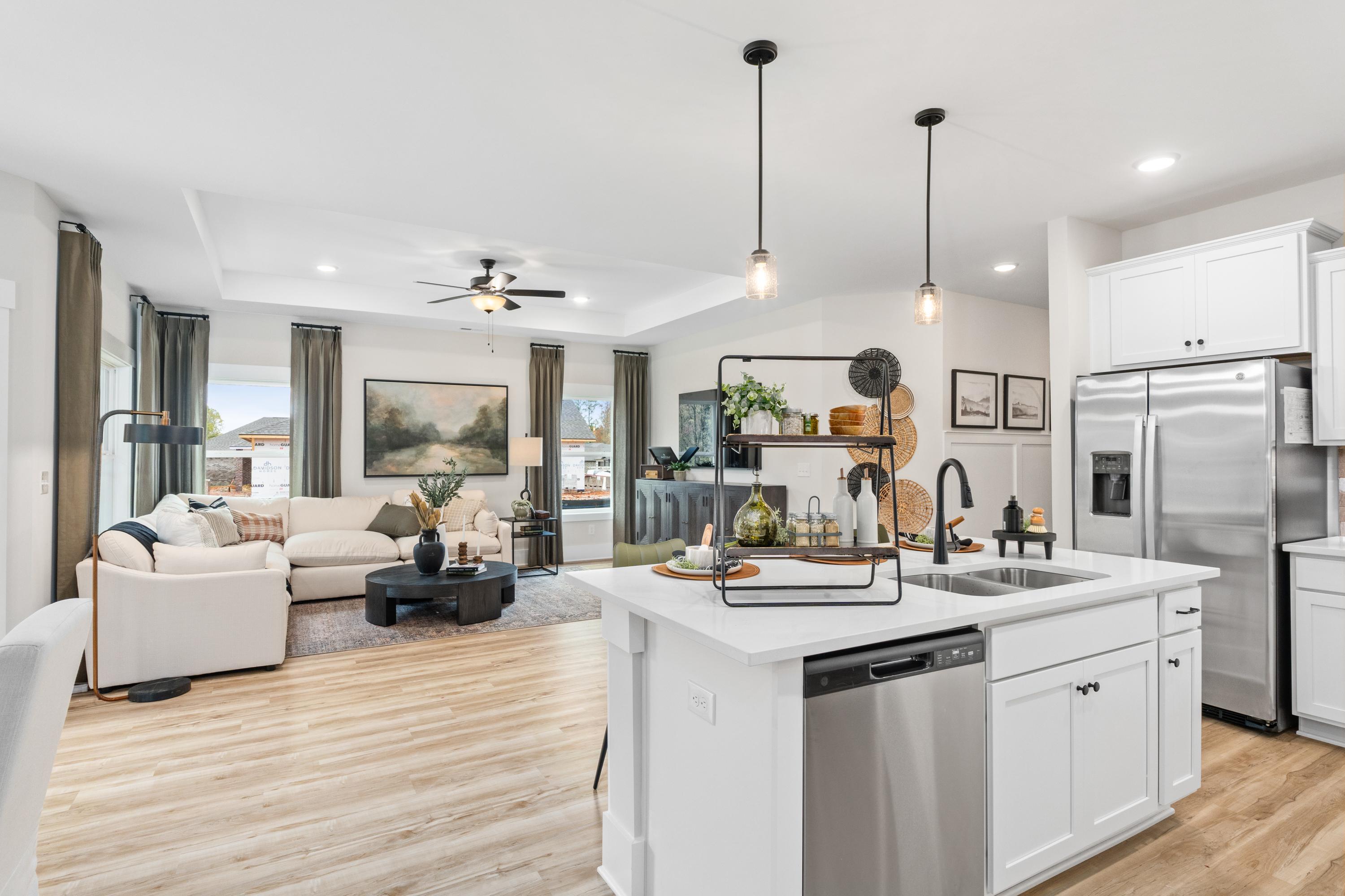 Open-concept kitchen and living room at Spragins Cove in Huntsville AL with white island hardwood floors and pendant lighting