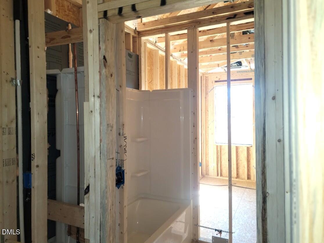 Unfinished bathroom with white bathtub and glass shower enclosure in Davidson Homes The Ashport G, Angier NC
