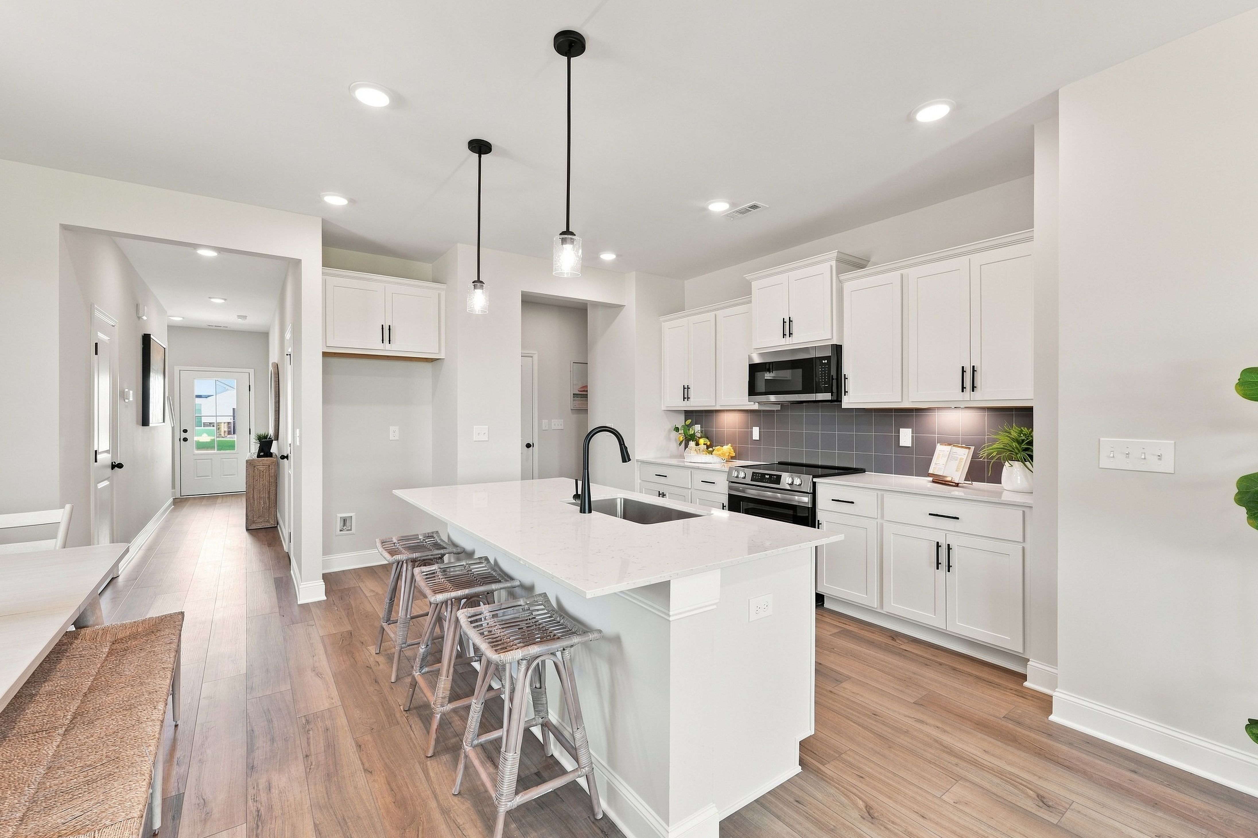 White kitchen with island, quartz countertops, and pendant lighting at Bailey Park by Davidson Homes in Fayetteville, Tennessee