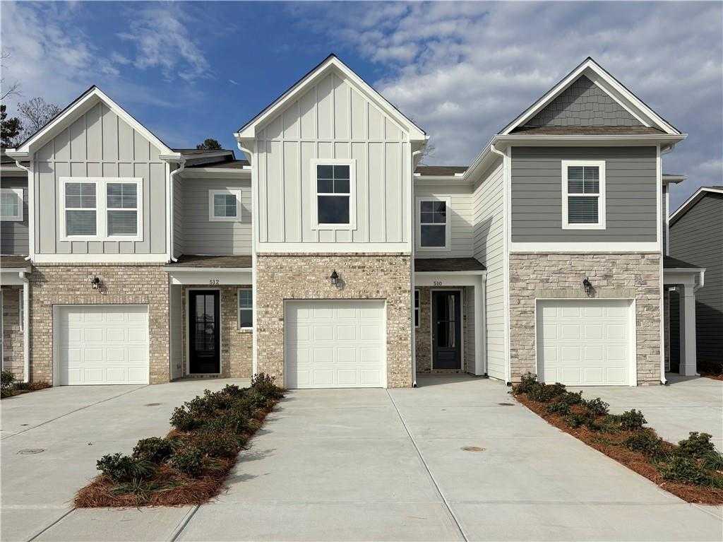 Row of three modern 2-story townhomes with white-gray siding, brick bases, 1-car garages in Stegall Village, Emerson, Georgia