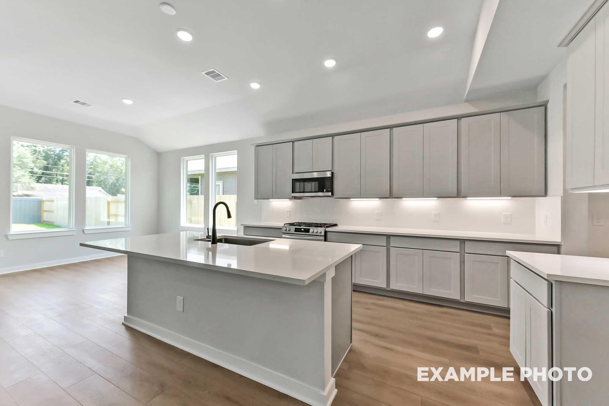 Spacious modern kitchen in The Sequoia by Davidson Homes with large gray island, quartz counters, stainless appliances, and open layout