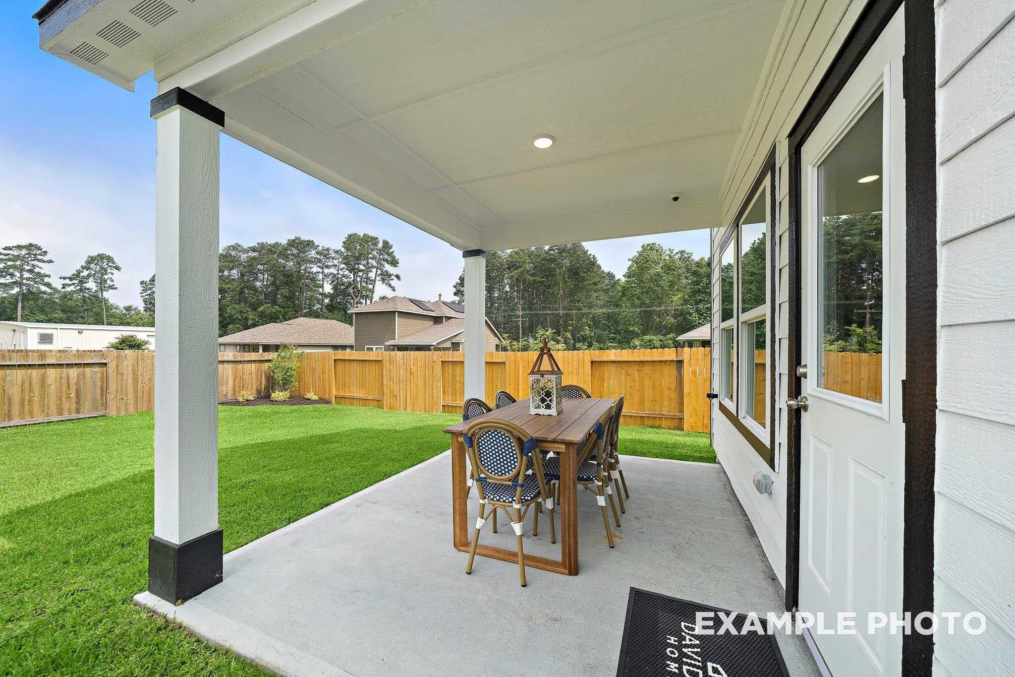 Covered patio with wooden dining table and chairs overlooking lush green backyard in Davidson Homes The San Marcos E, Conroe, Texas