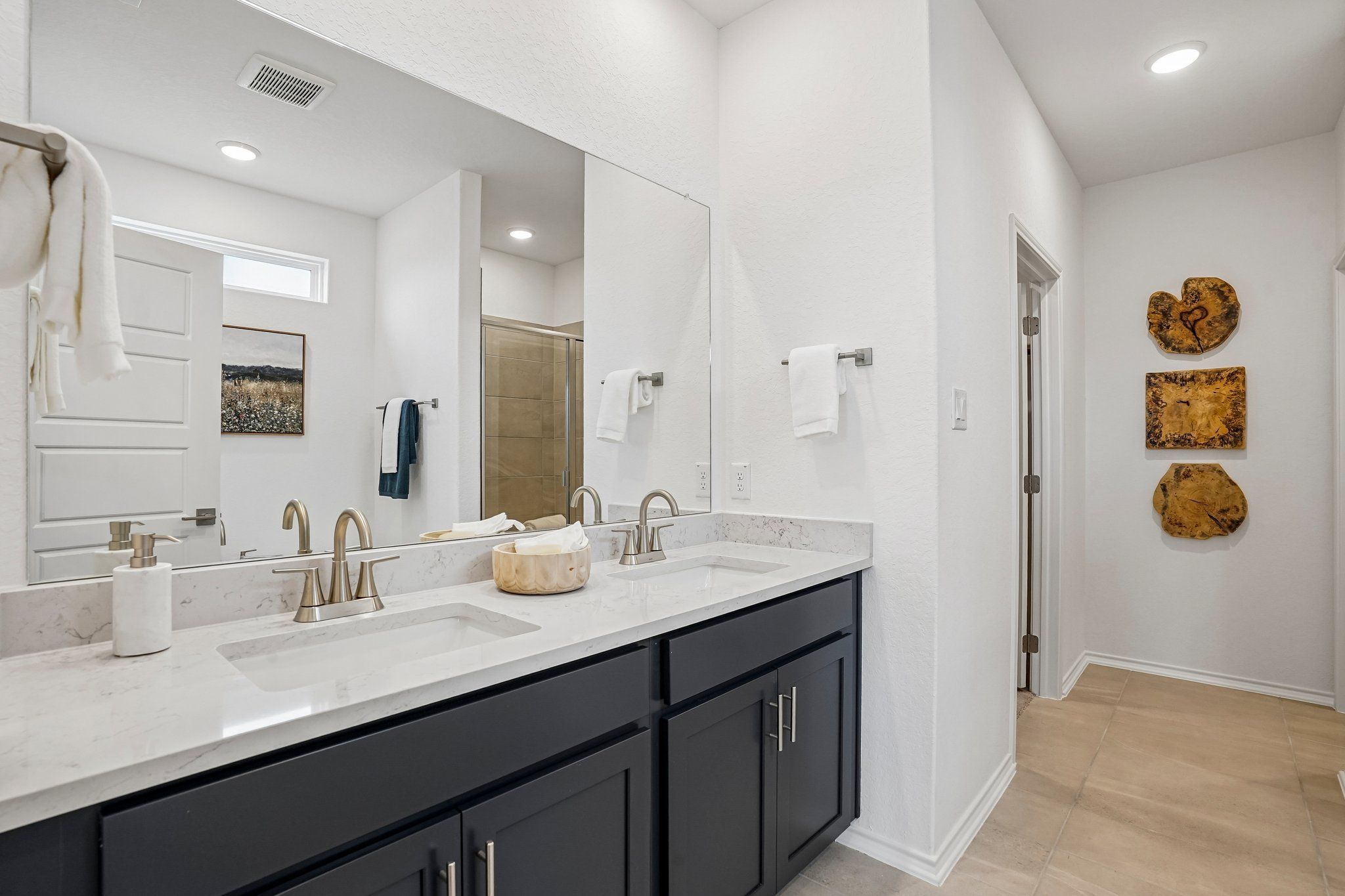 Modern primary bathroom with double vanity, quartz countertops, and dark cabinetry at Morgan Meadows in San Antonio, Texas.