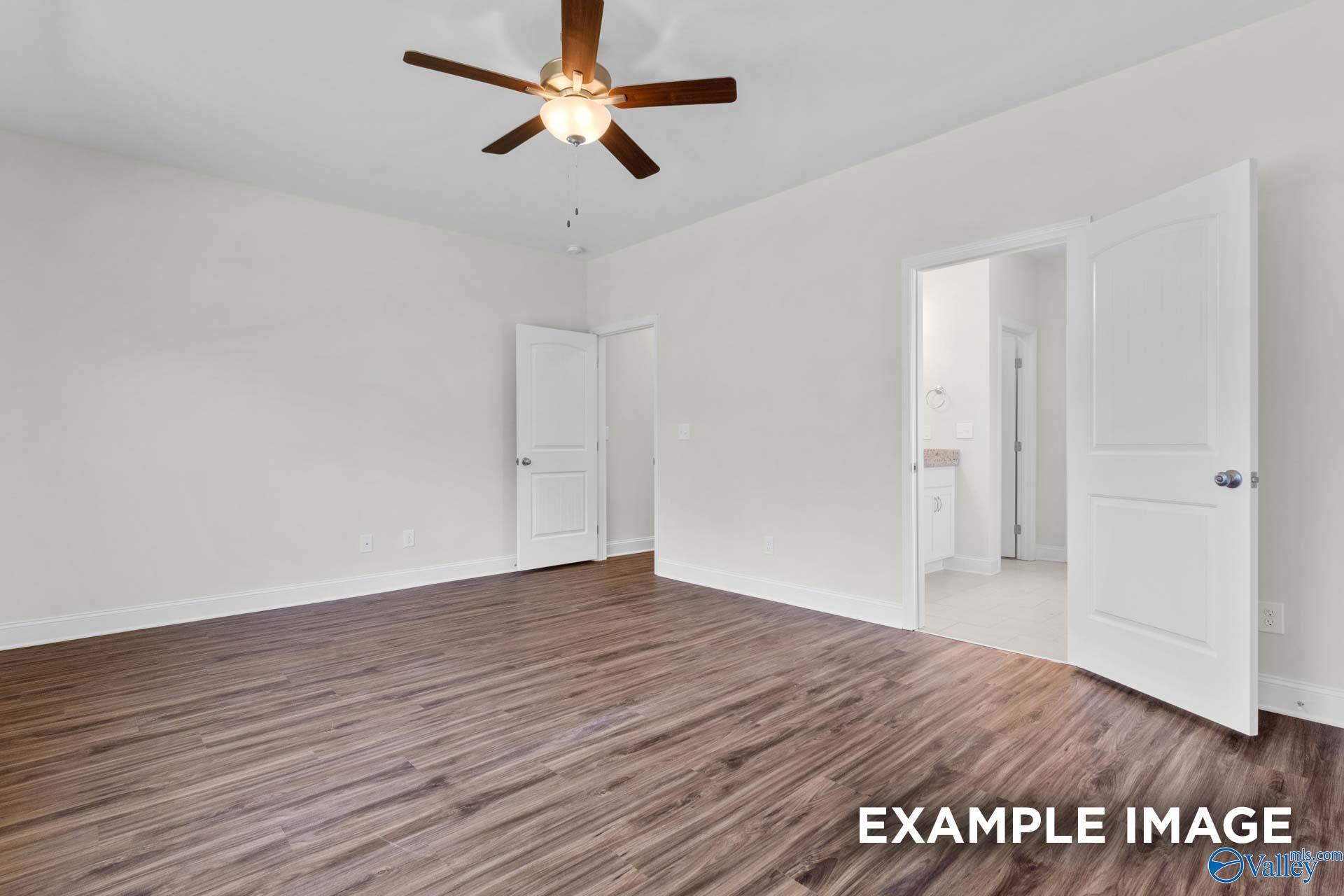 Spacious master bedroom with ceiling fan, hardwood floors, and open en-suite bathroom in Davidson Homes Montgomery C, Harvest, AL