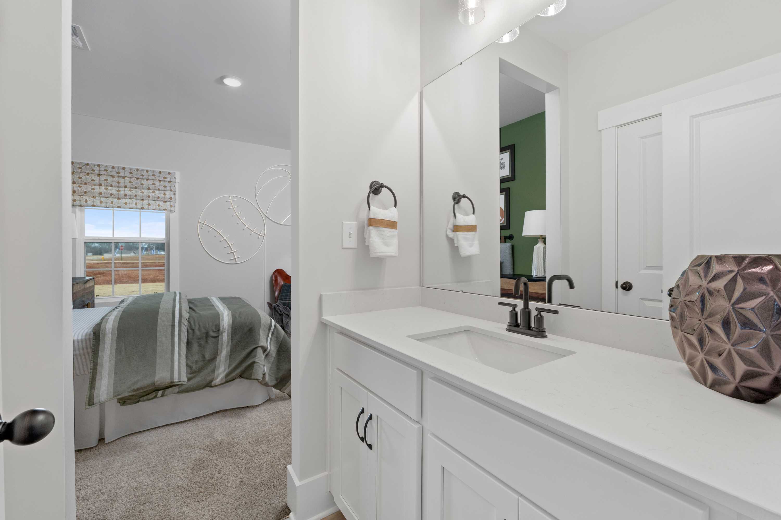 Spacious white bathroom with vanity sink and mirror adjacent to baseball-themed bedroom in Briercreek, Meridianville Alabama