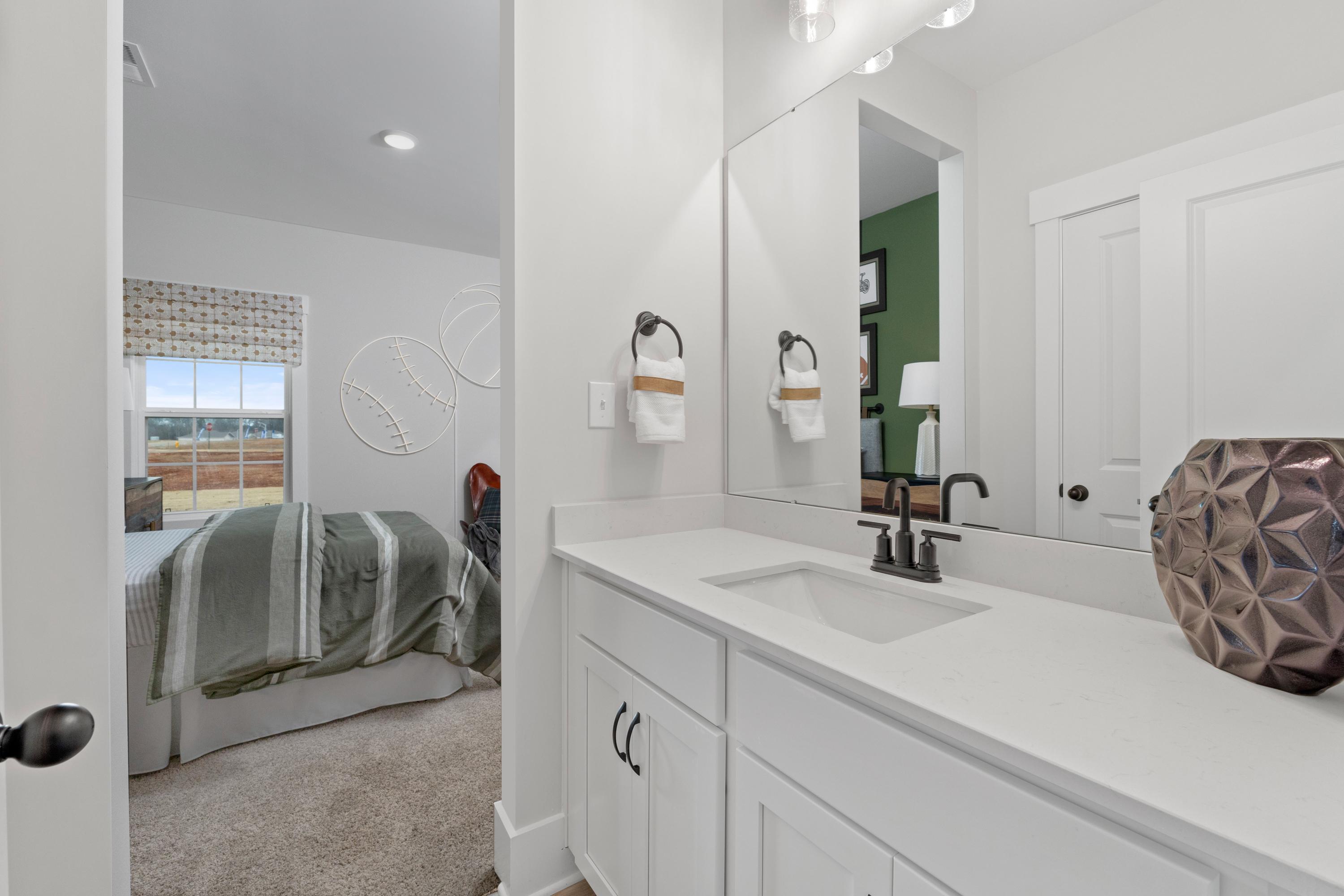 Spacious white bathroom with vanity sink and mirror adjacent to baseball-themed bedroom in Briercreek, Meridianville Alabama