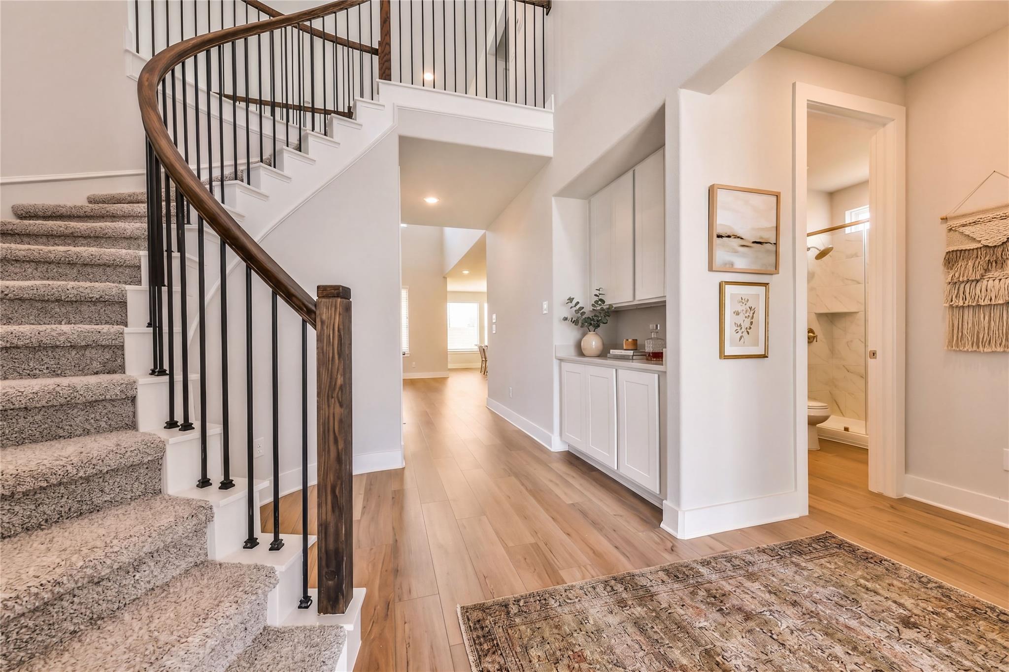 Elegant curved wooden staircase with black iron railings in two-story foyer of Davidson Homes Victoria A, Lago Mar, Texas City
