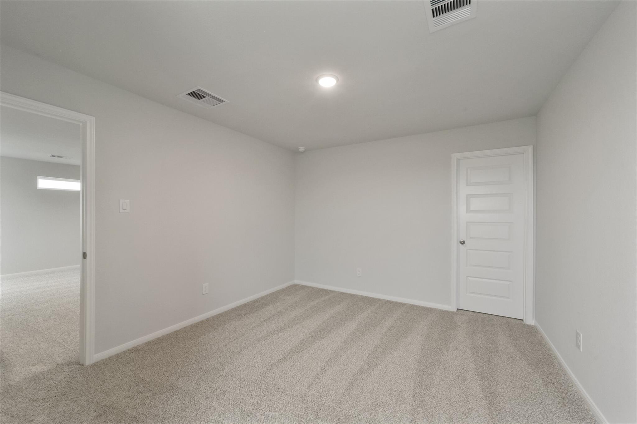 Spacious empty bedroom with beige carpet, white walls, and open closet door in The San Marcos E 5-bedroom home, Beasley, Texas