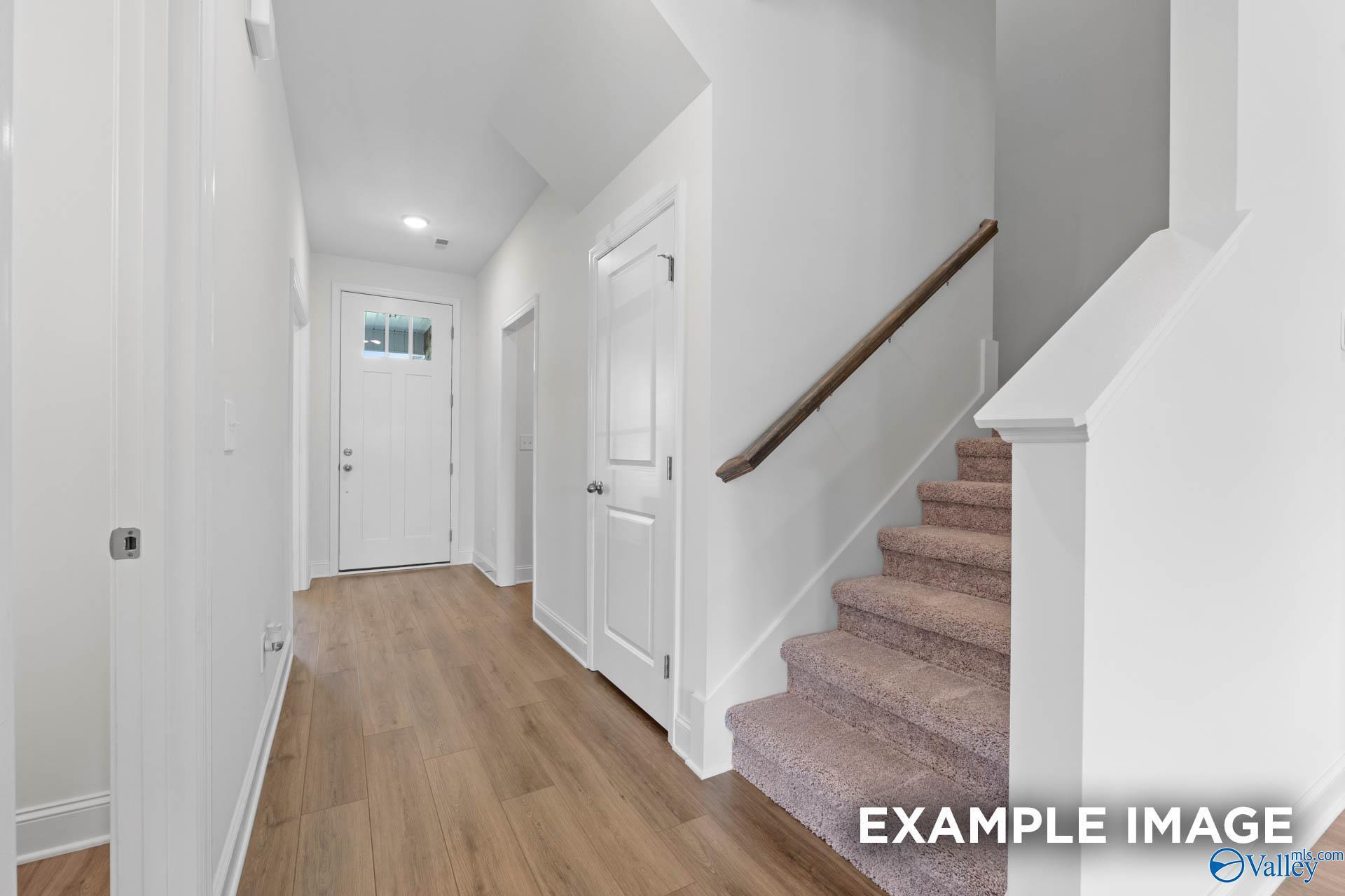 Bright foyer with wood-look flooring and carpeted staircase in The Rockford B floor plan at Kendall Downs, Toney, AL.