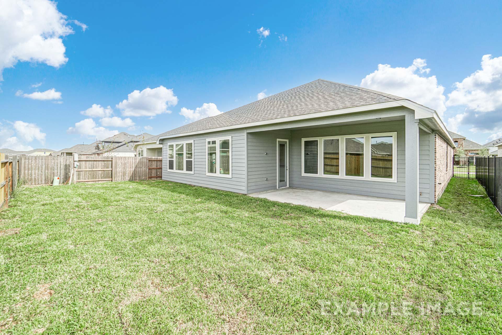 Rear view of The George B single-story home with covered patio, large windows, and lush green backyard in Rosharon TX
