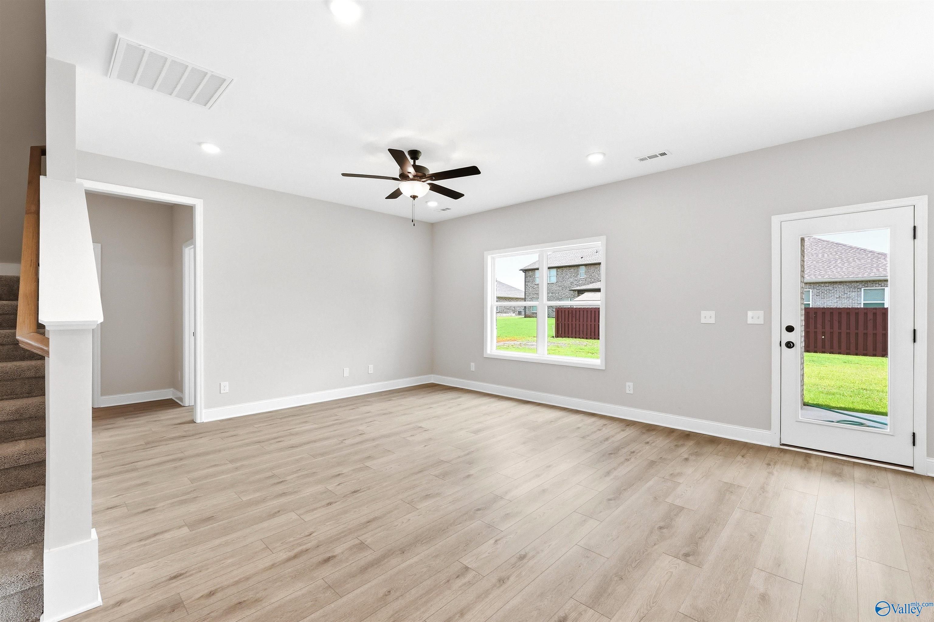 Bright, open-concept living area with wood-style flooring in The Shelby A floor plan at Wood Trail in Toney, Alabama.