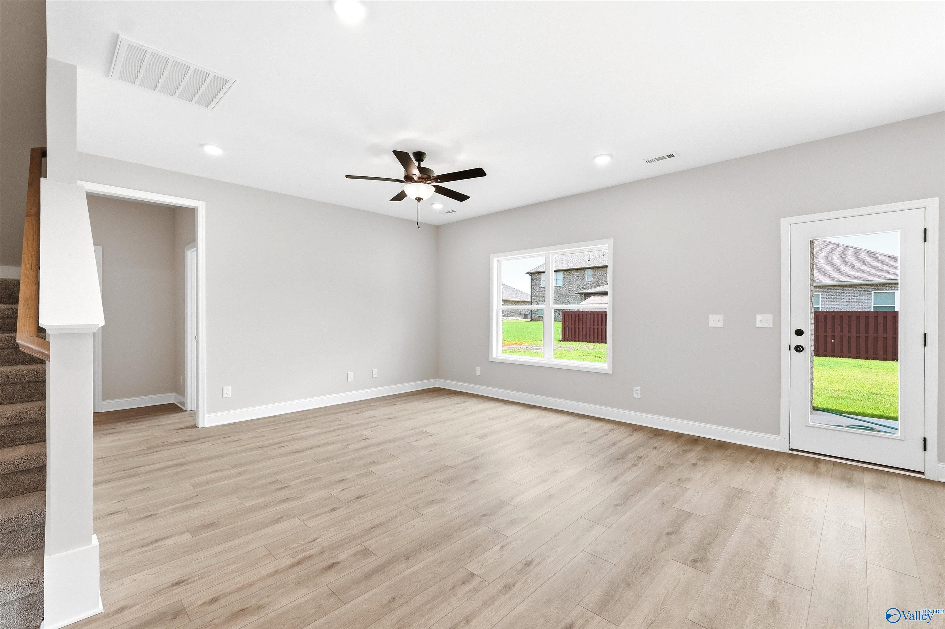 Bright, open-concept living area with wood-style flooring in The Shelby A floor plan at Wood Trail in Toney, Alabama.