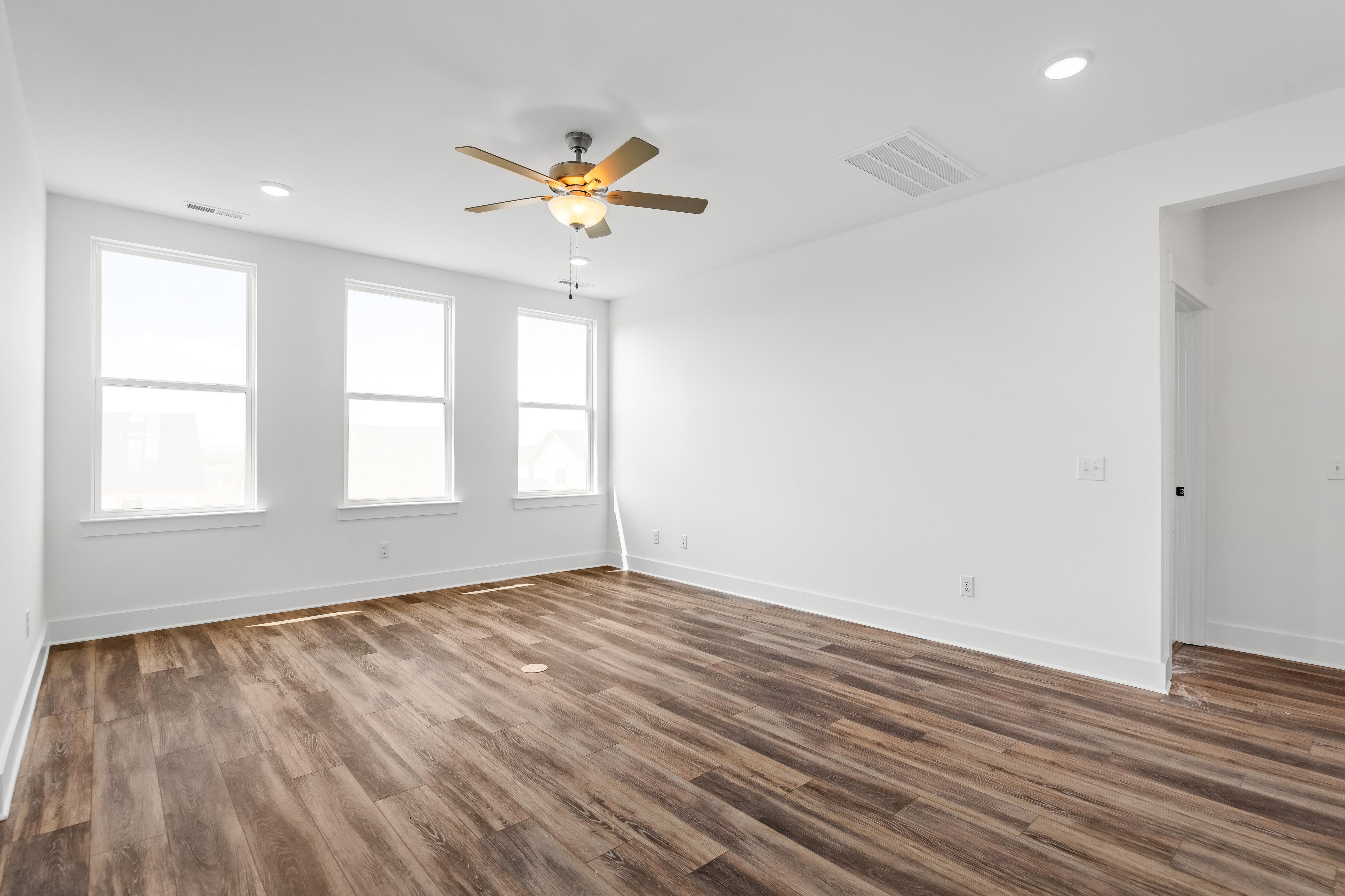 Spacious master suite with wood-look flooring and ceiling fan in The Cedar D home design by Davidson Homes.