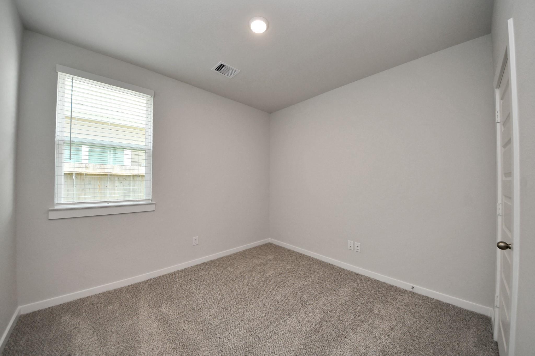 Empty bedroom with beige carpet, white walls, and window with blinds in Davidson Homes The Frio F floor plan, Robins Landing, Houston