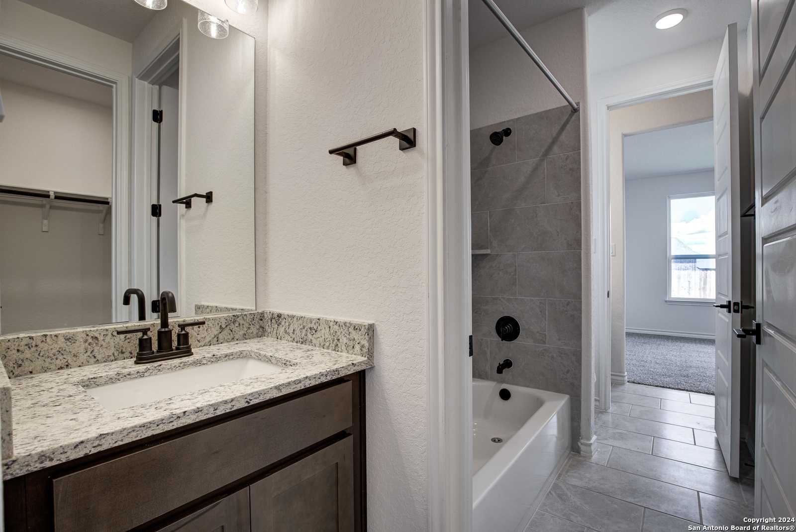 Elegant bathroom with quartz vanity, glass-enclosed shower, soaking tub in Davidson Homes The Garner B, Castroville TX