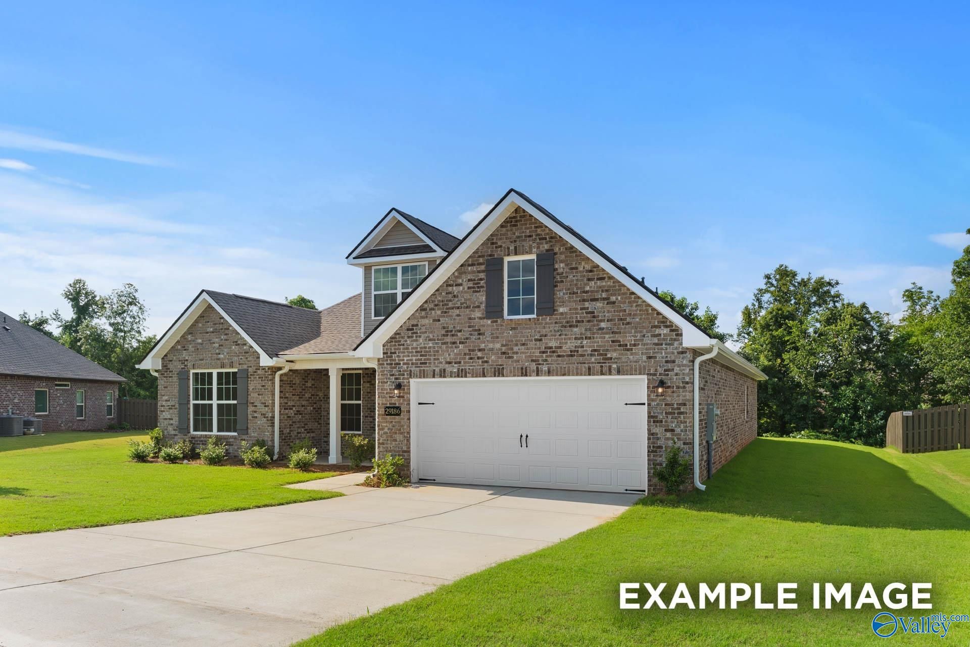 Modern 1.5-story brick home with 2-car garage, driveway, and green lawn in Barnett's Crossing, Madison, Alabama