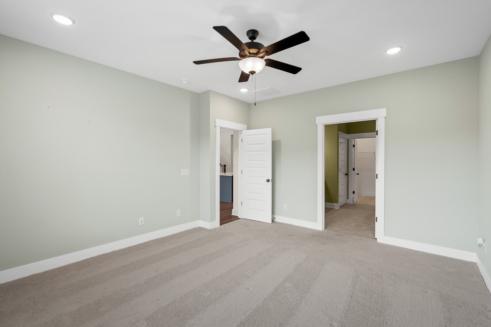 Spacious secondary bedroom with sage green walls, ceiling fan, and en-suite bath in Davidson Homes The Ridgeport, Gallatin, TN