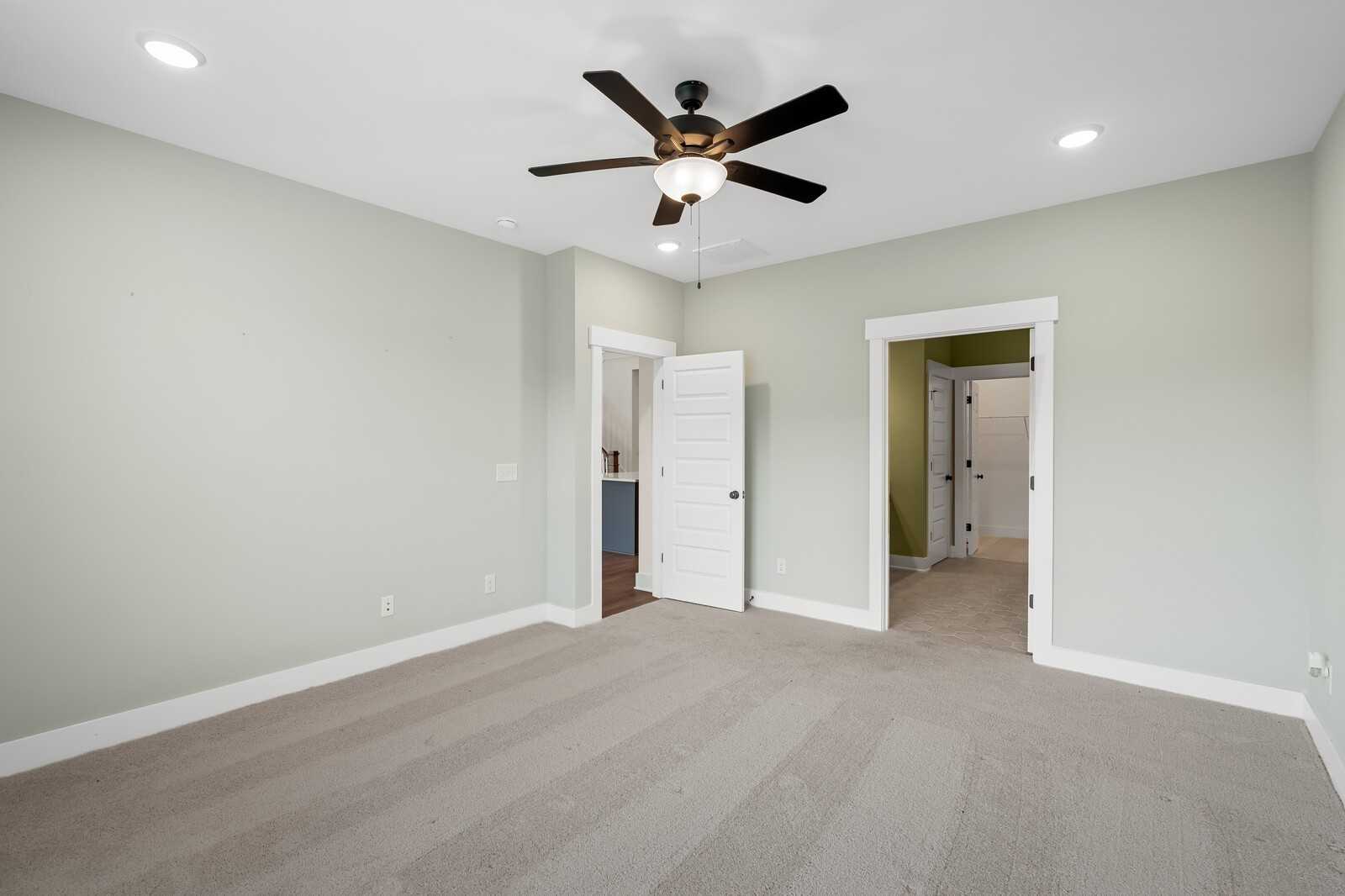 Spacious secondary bedroom with sage green walls, ceiling fan, and en-suite bath in Davidson Homes The Ridgeport, Gallatin, TN