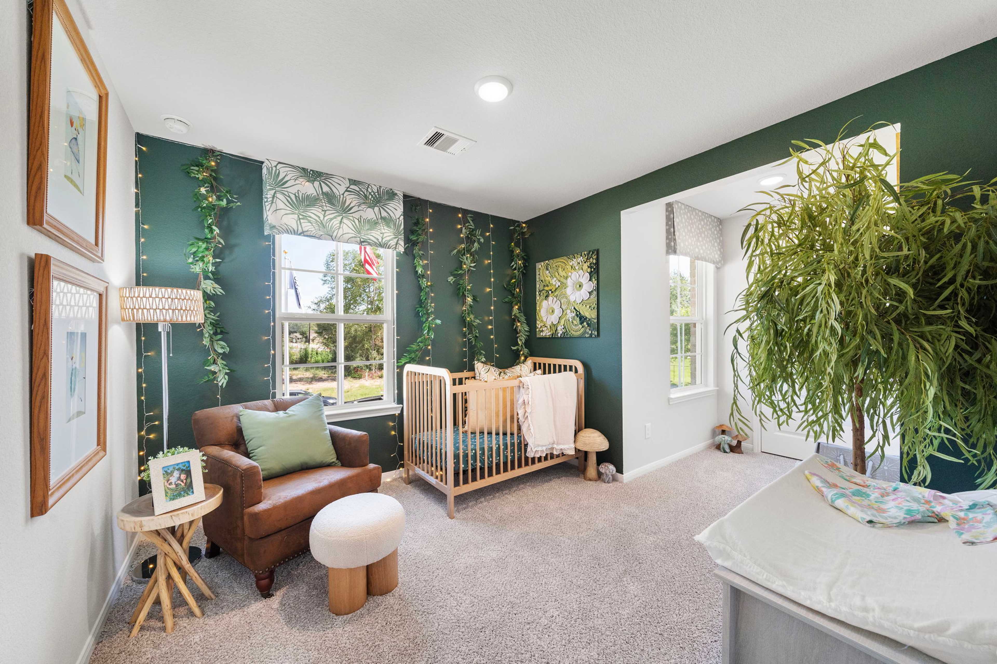 Cozy green nursery with wooden crib, leather armchair, potted plants and fairy lights at Caney Creek Place in Conroe Texas