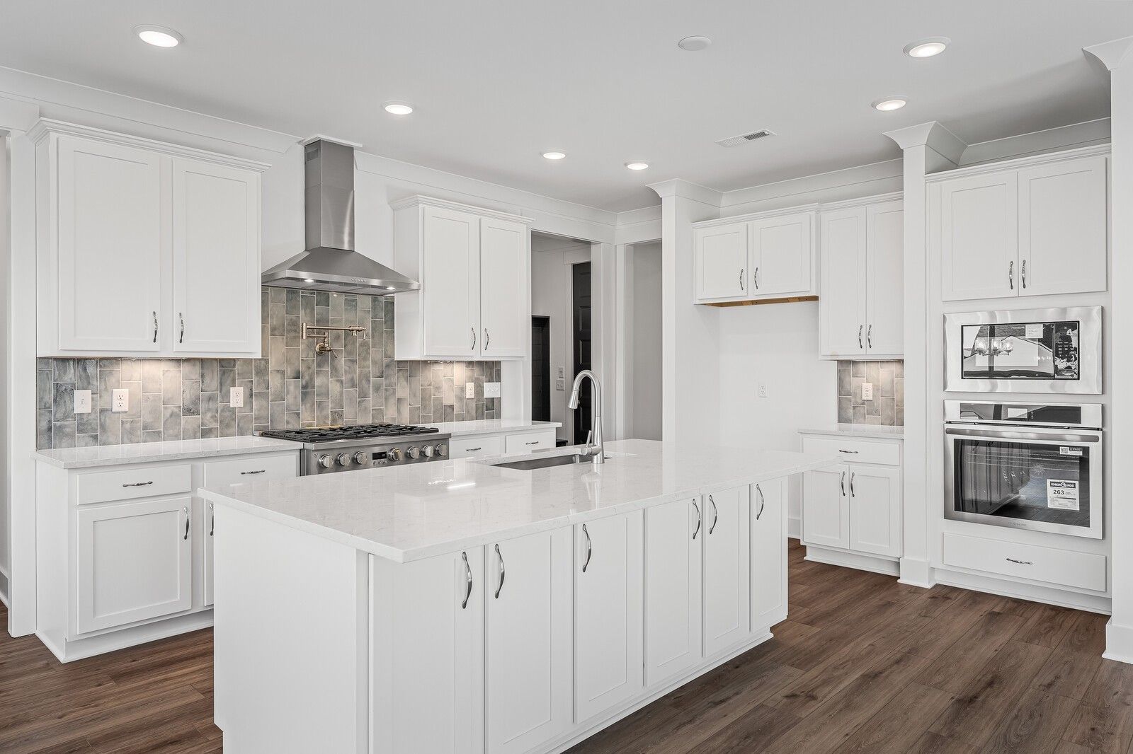 Modern white kitchen with large island sink, stainless steel appliances, subway tile backsplash in Davidson Homes The Hawkins, Murfreesboro, TN