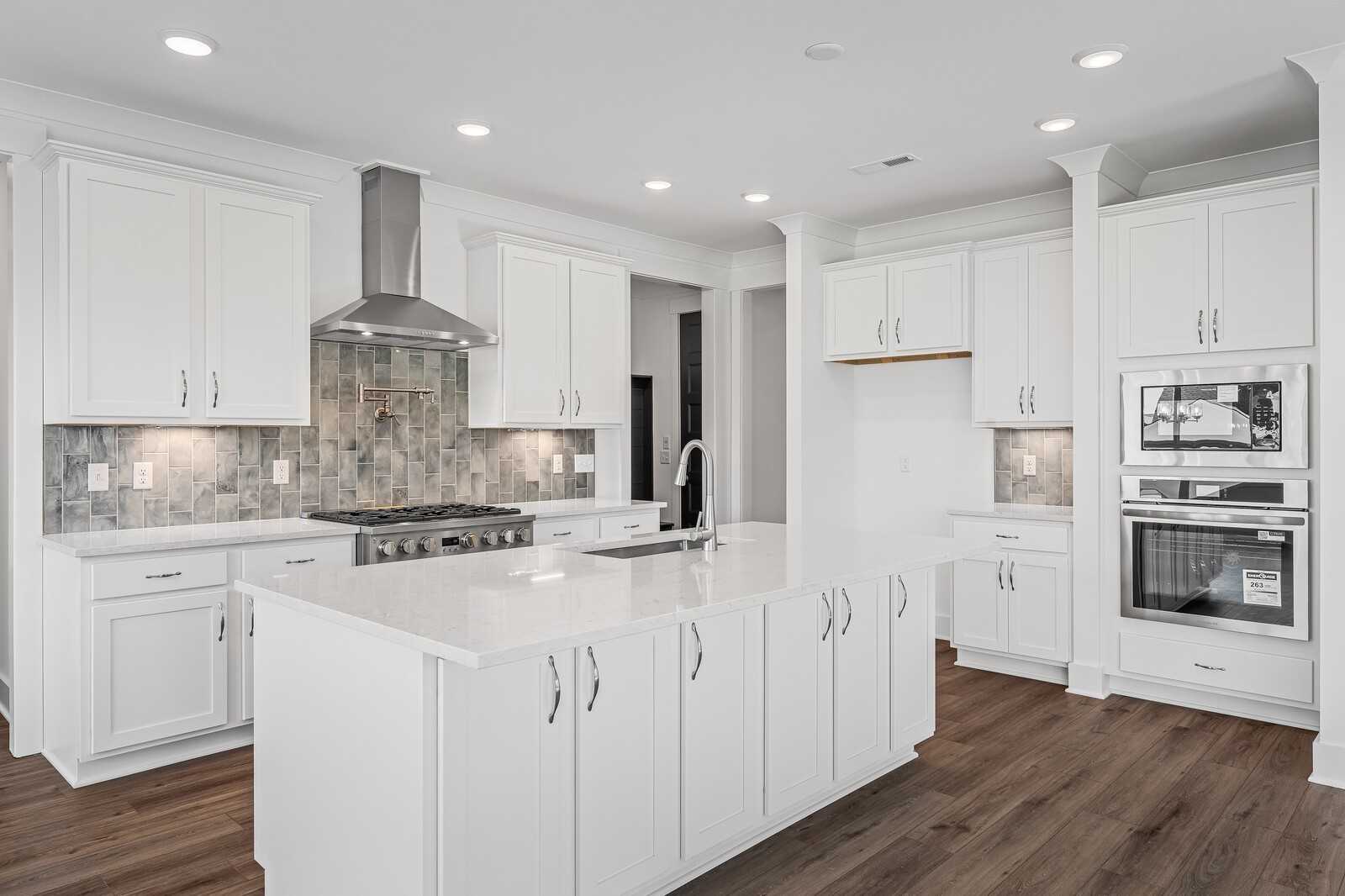 Modern white kitchen with large island sink, stainless steel appliances, subway tile backsplash in Davidson Homes The Hawkins, Murfreesboro, TN