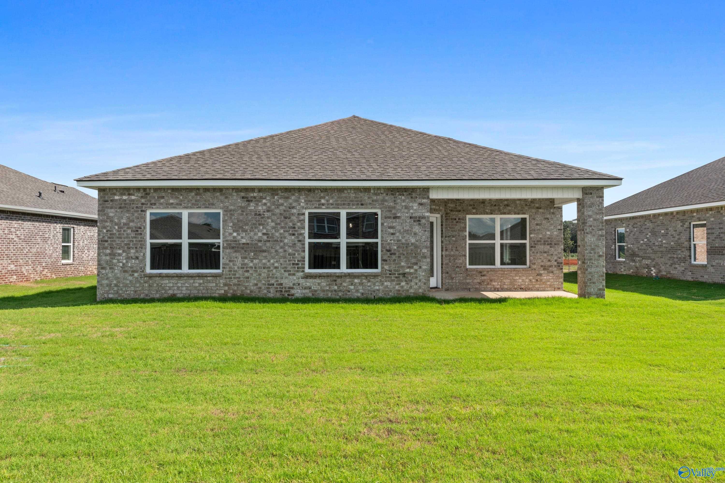 Single-story brick home with gabled roof, large windows, and front porch on lush green lawn in Clearview, Hazel Green, Alabama - Davidson Homes Franklin C