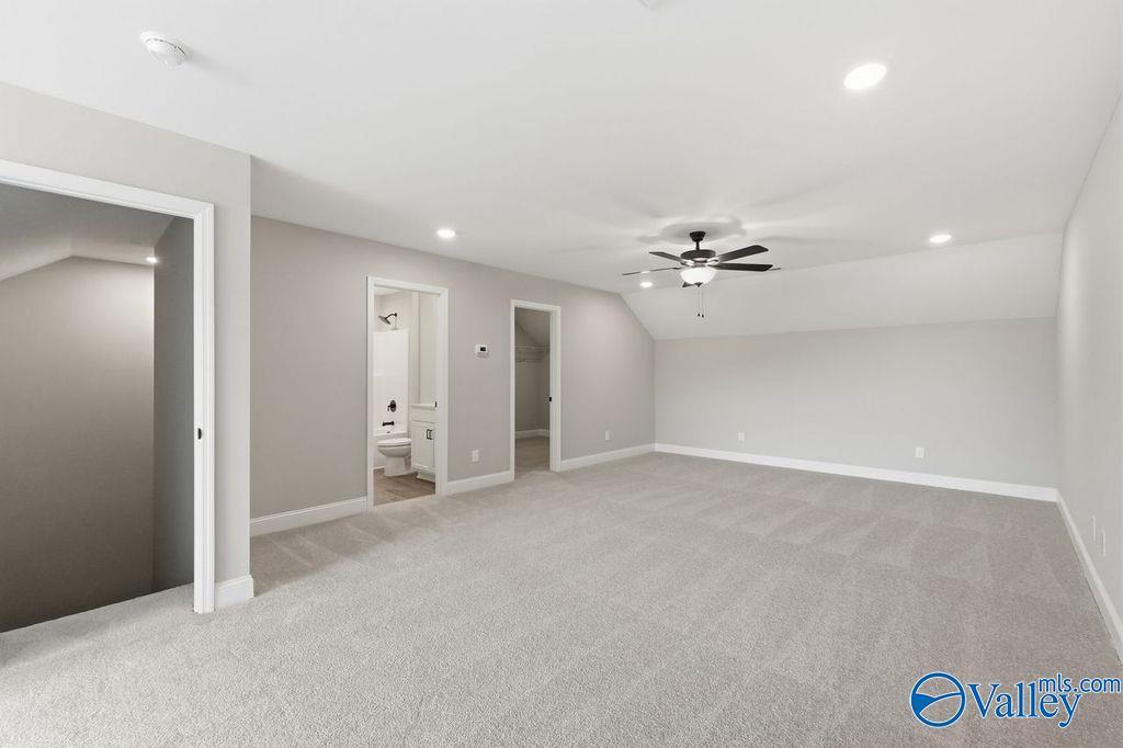 Spacious bonus room with vaulted ceiling and carpet in The Rockford floor plan by Davidson Homes in Cain Park, Hartselle.