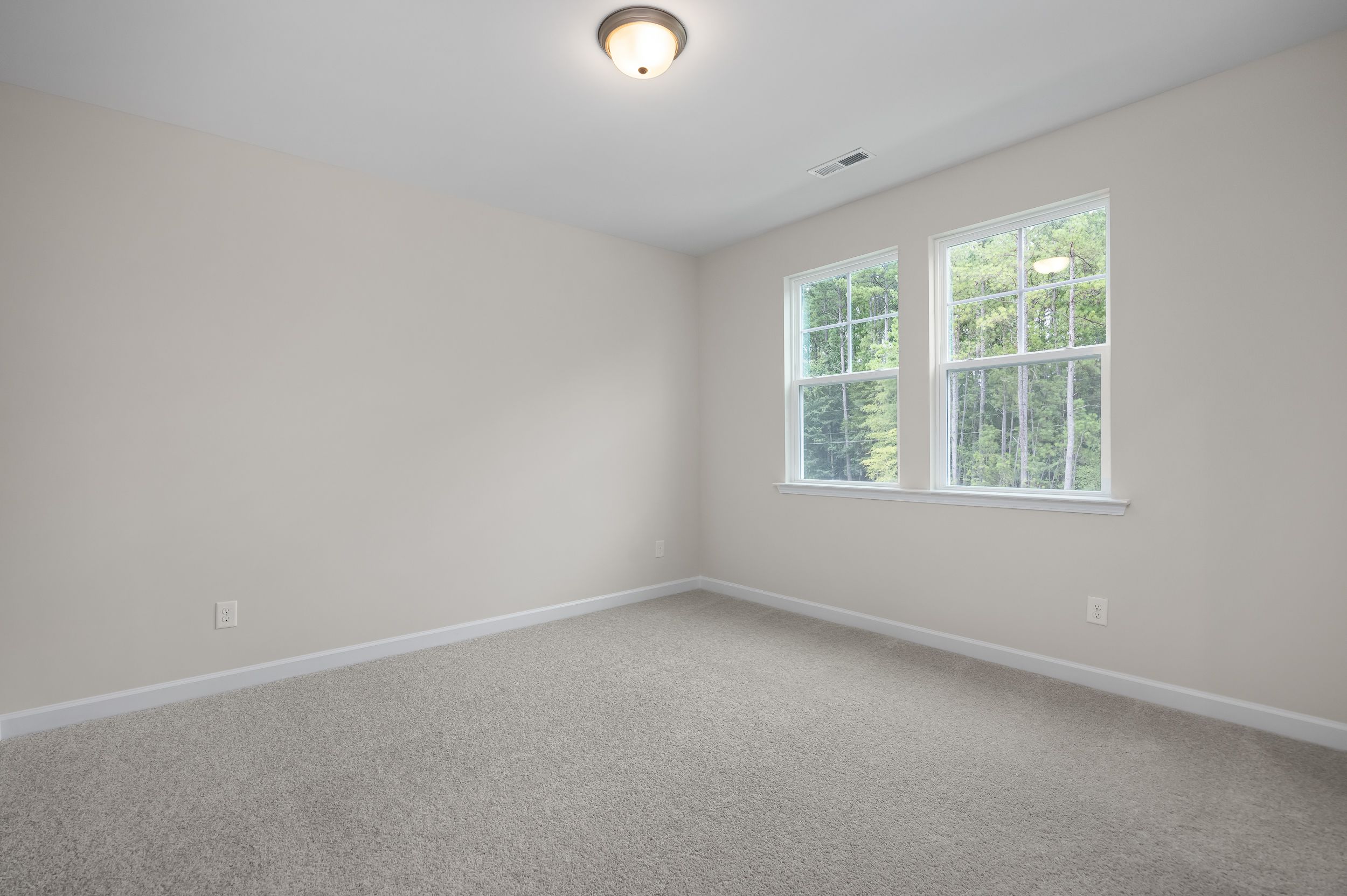 Spacious upstairs bedroom in The Beech A with beige walls, double windows overlooking trees, ceiling light, and carpeted floor
