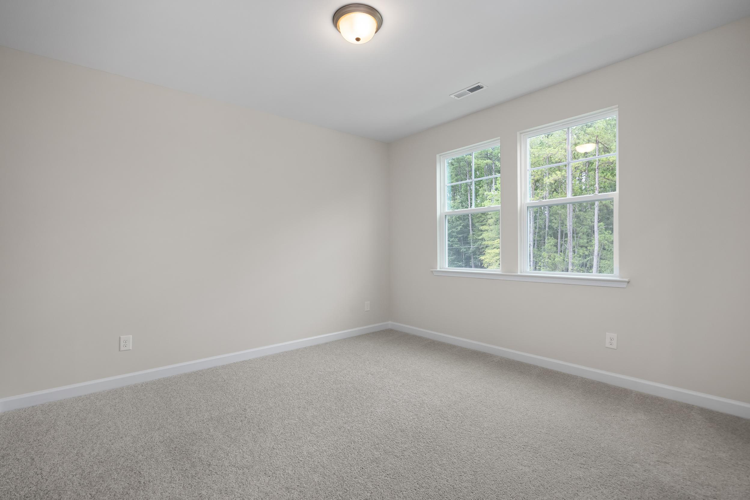 Spacious upstairs bedroom in The Beech A with beige walls, double windows overlooking trees, ceiling light, and carpeted floor